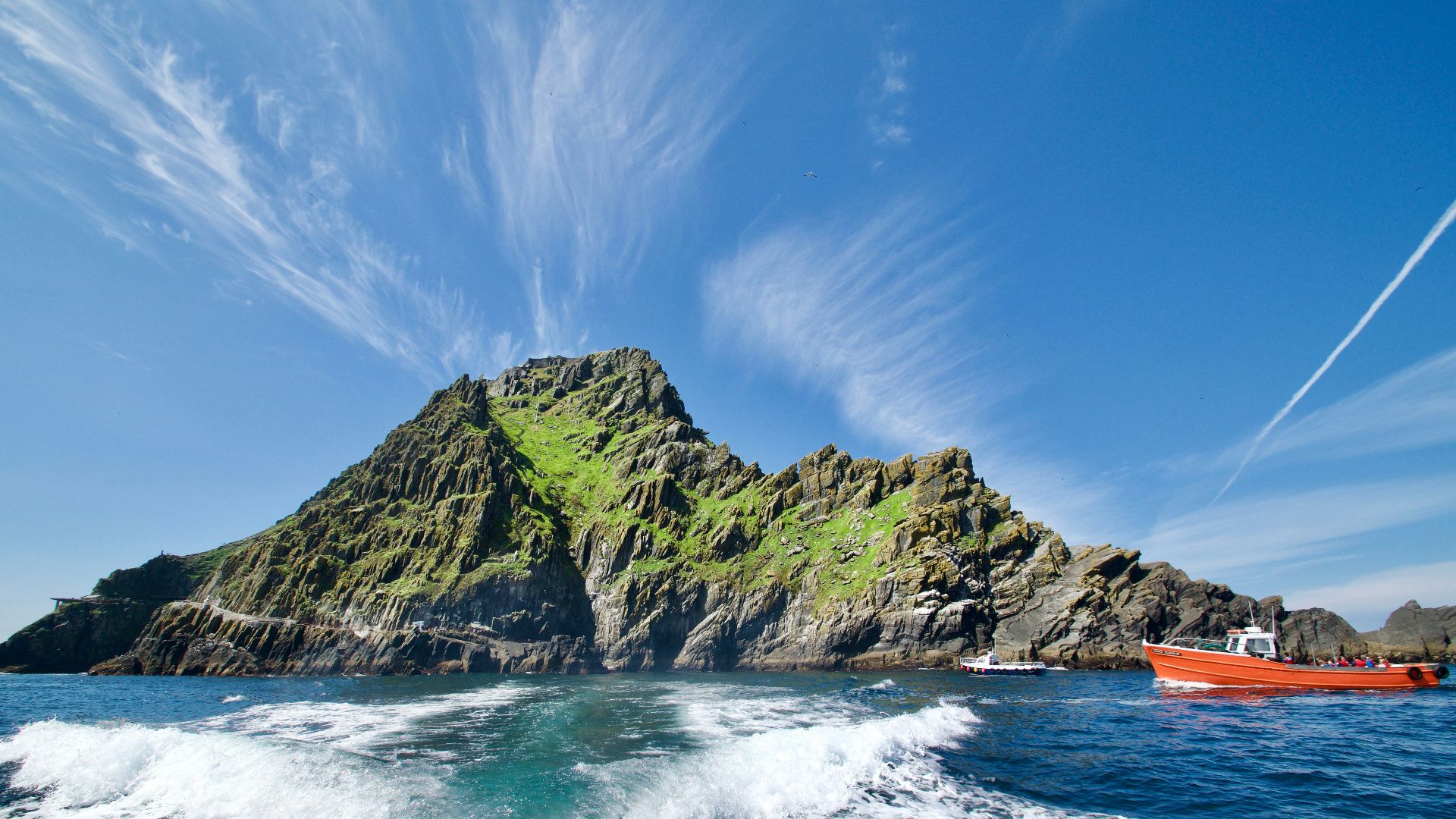 green and brown rock formation on sea under blue sky during daytime