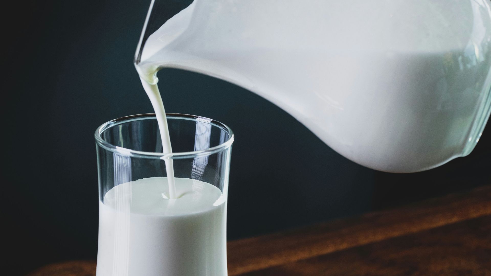 person pours milk into glass