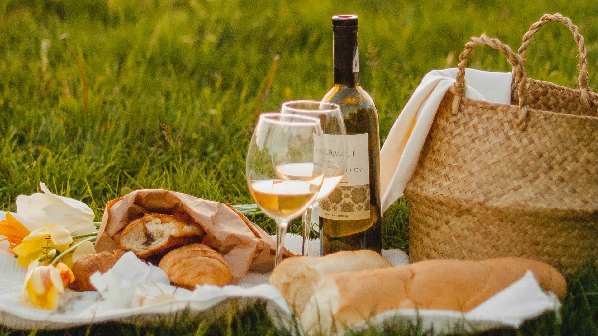 clear glass bottle beside brown wicker basket on green grass during daytime