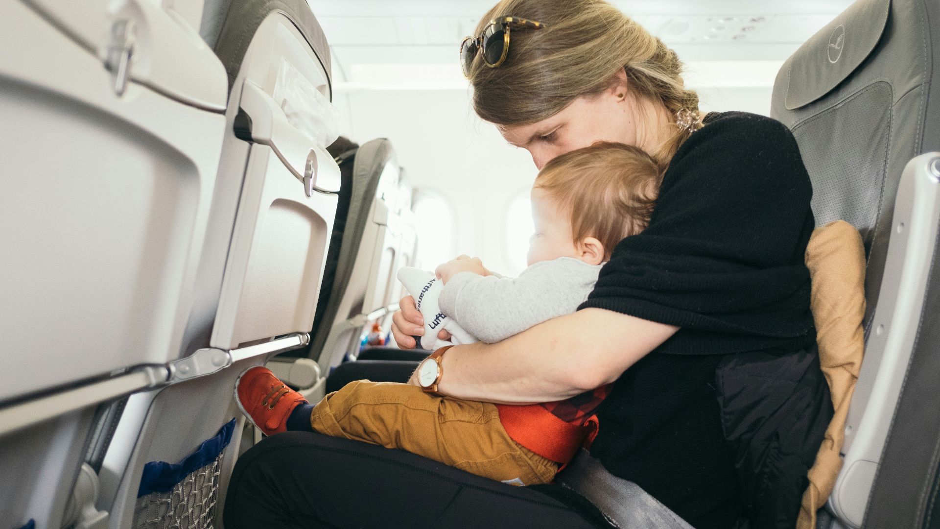 woman carrying baby while sitting on gray seat