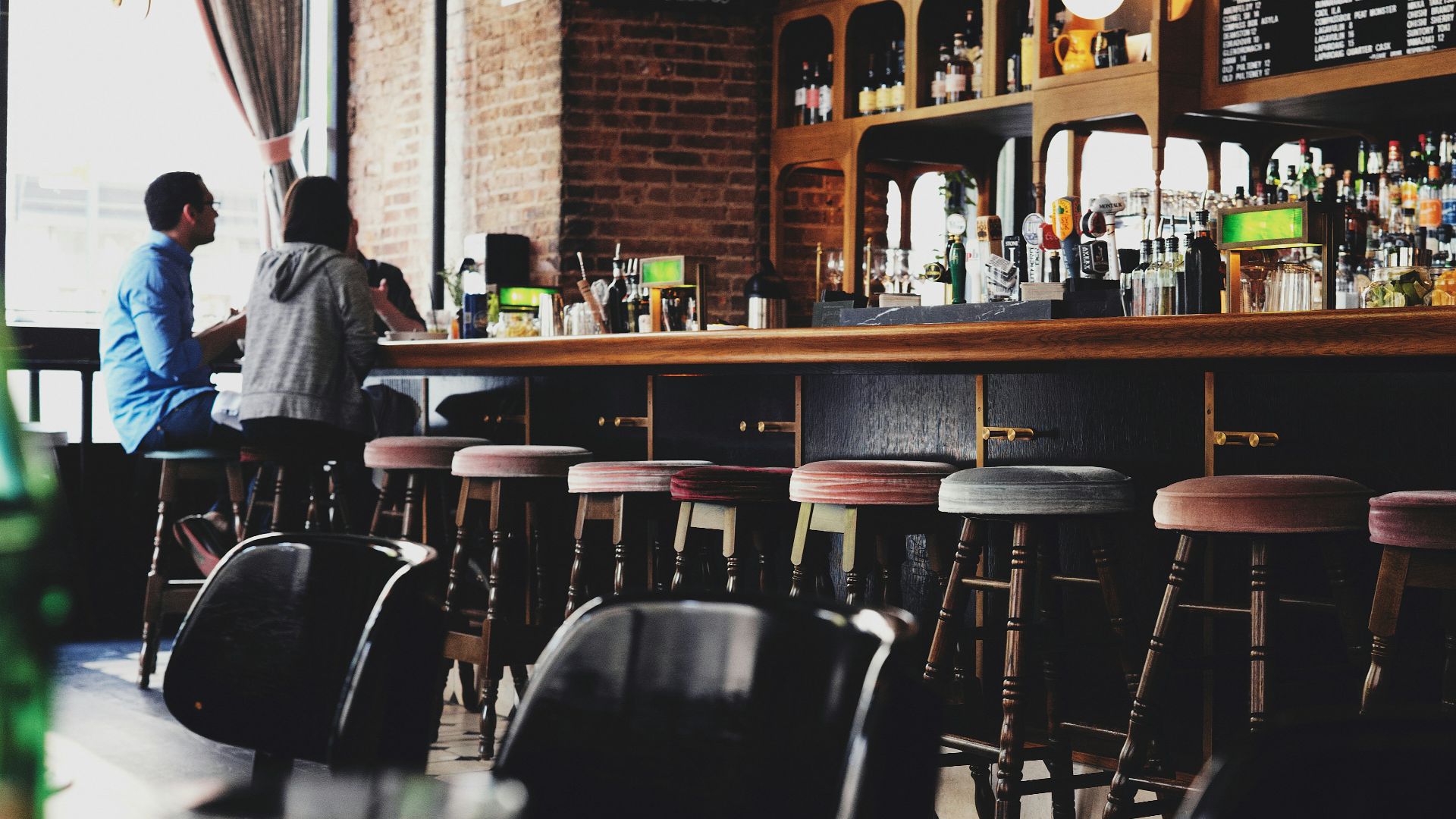 two person sitting on bar stool chair in front of bar front desk
