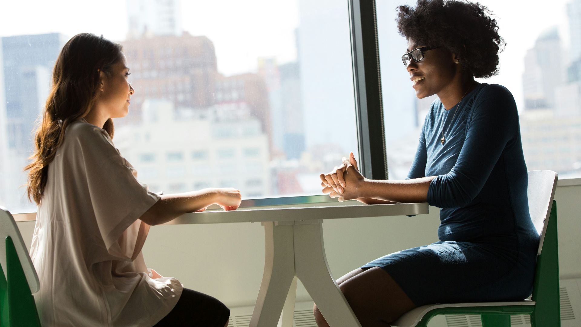 two women sitting beside table and talking