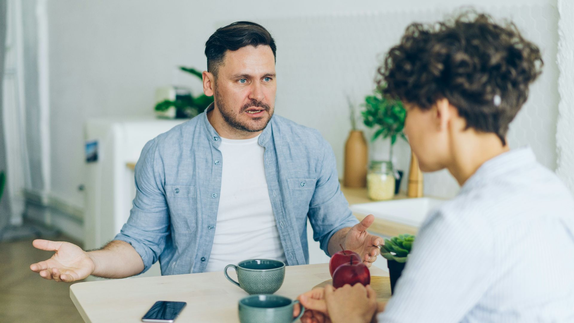 a man sitting at a table talking to a woman