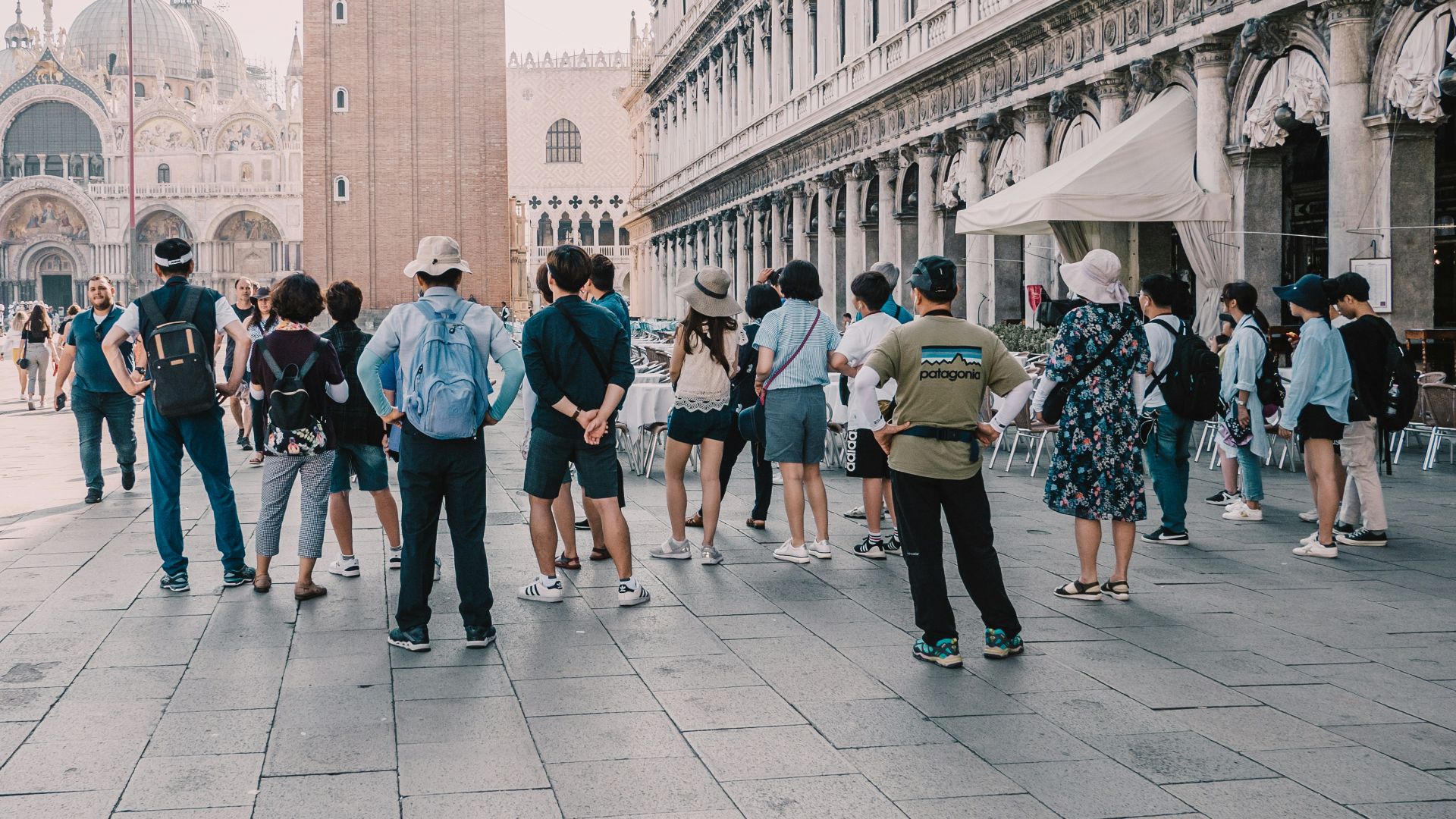 a group of people standing on a street next to a tall building