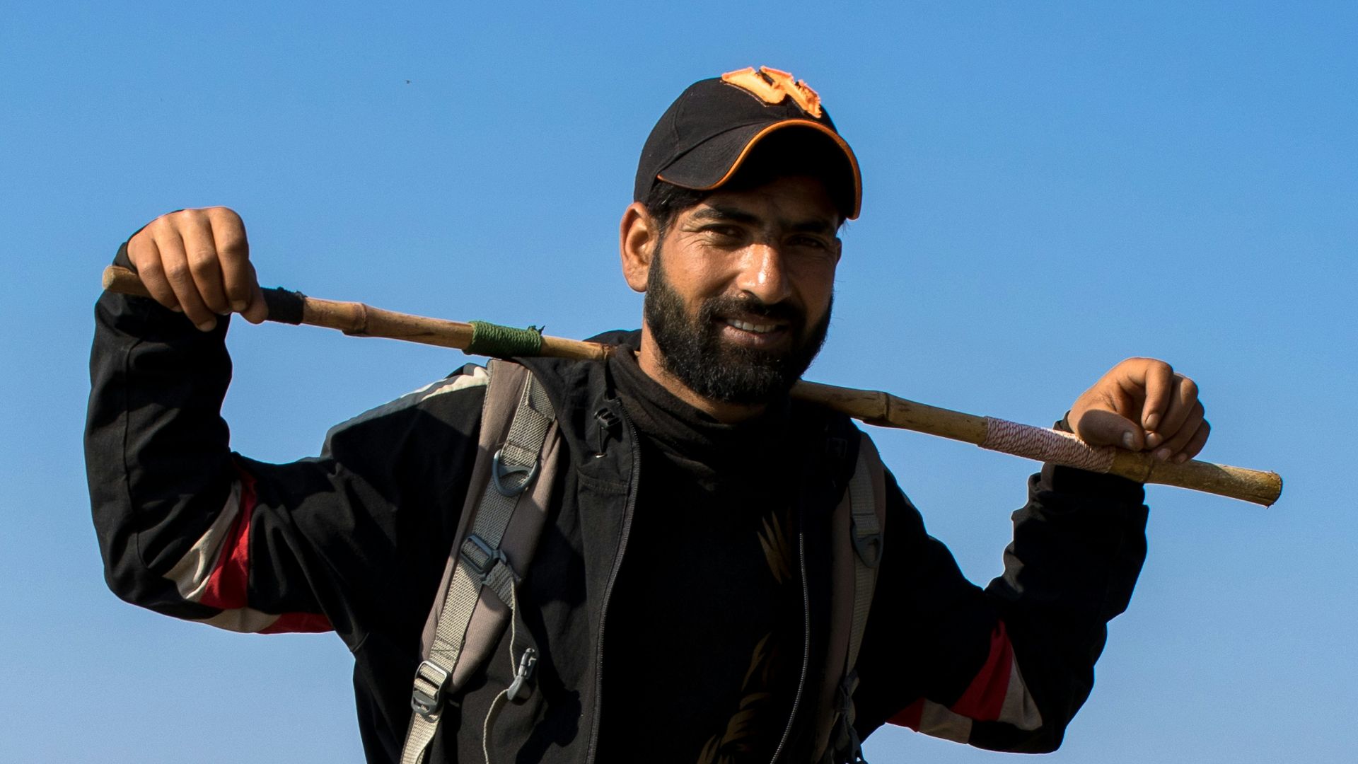 a man holding a stick and wearing a hat