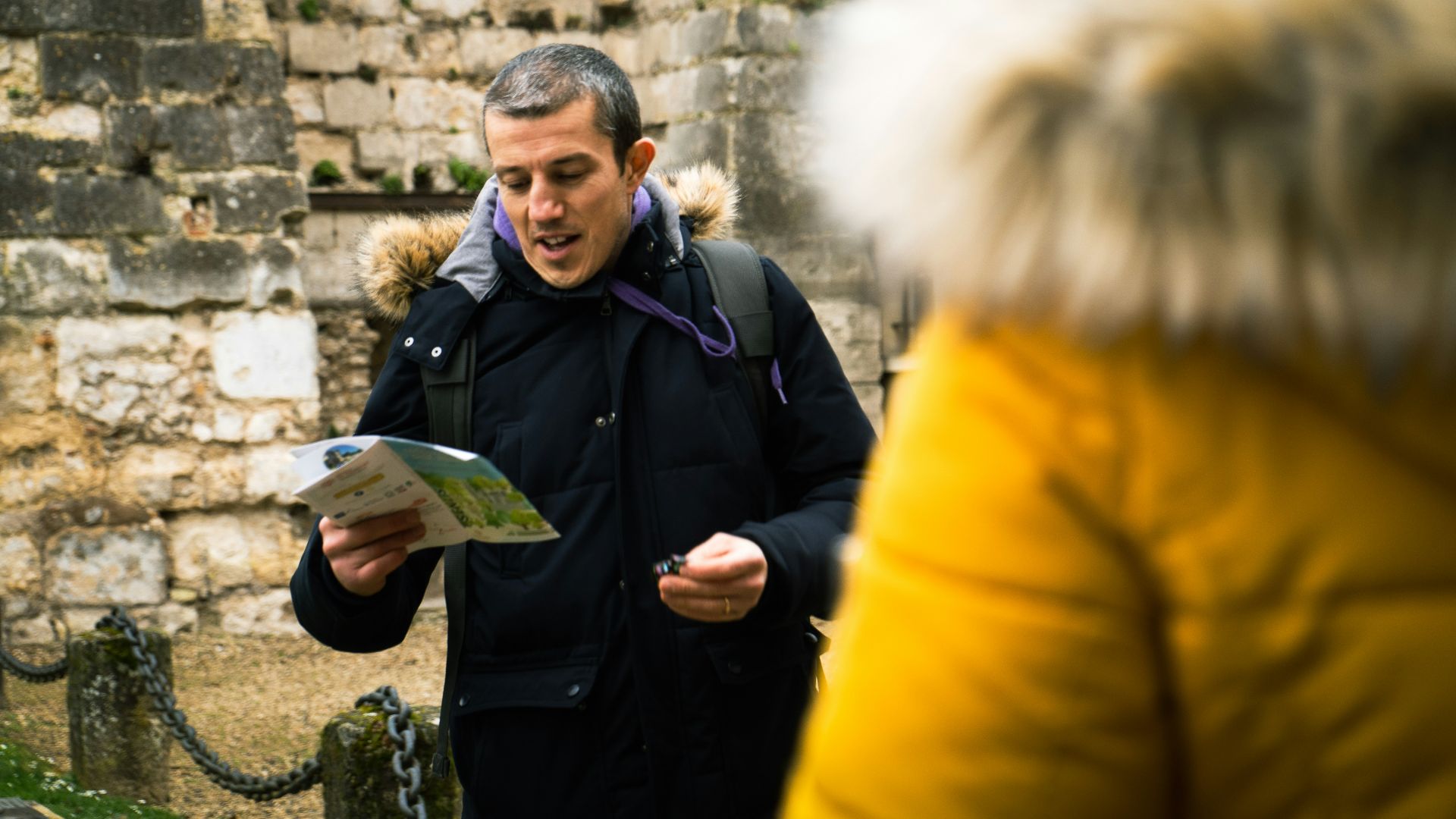 a man standing in front of a stone wall