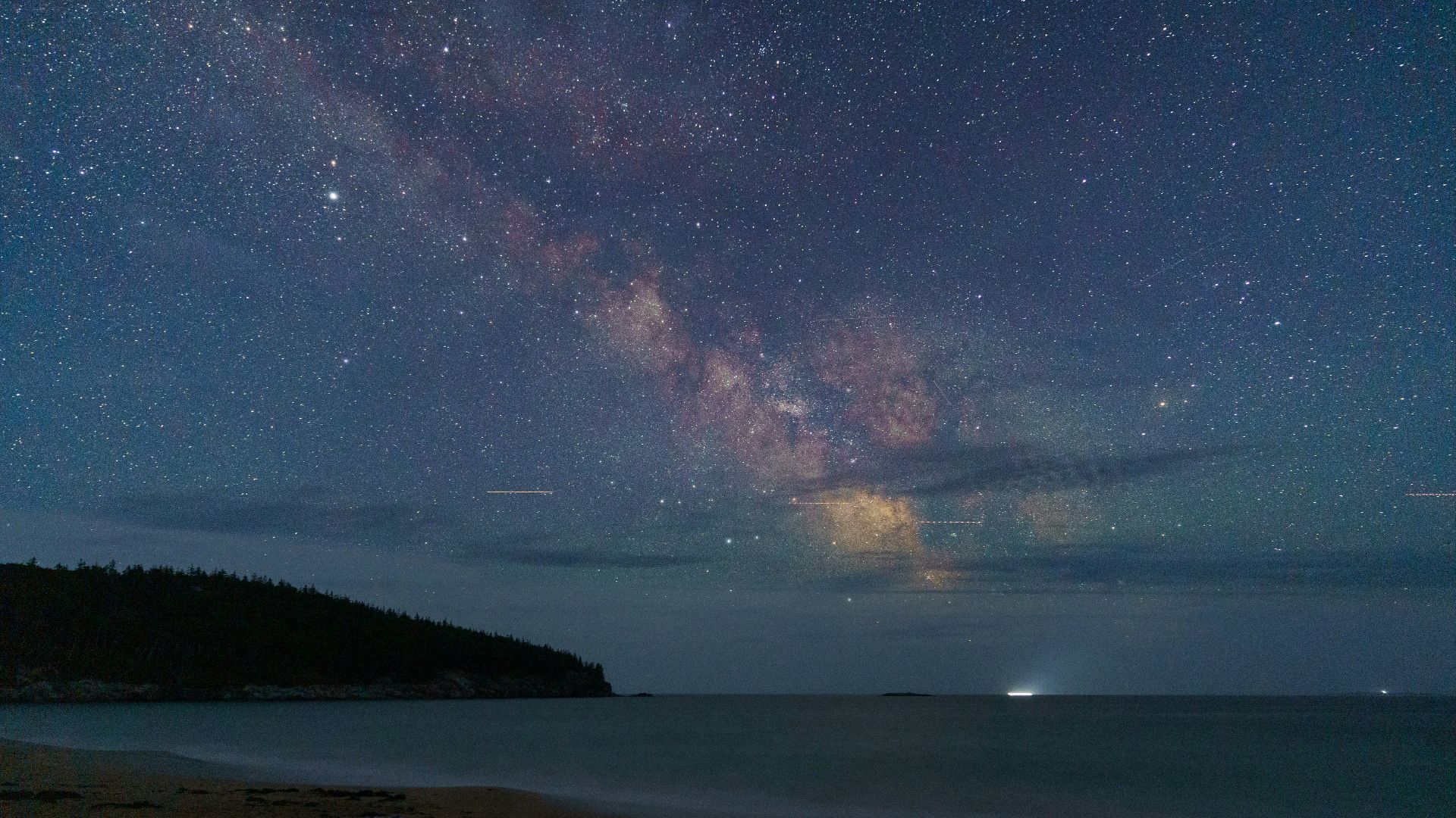 The milky way galaxy shimmers above a serene beach.