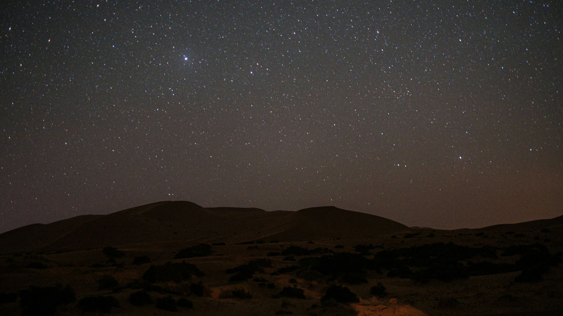 the night sky with stars above a desert landscape