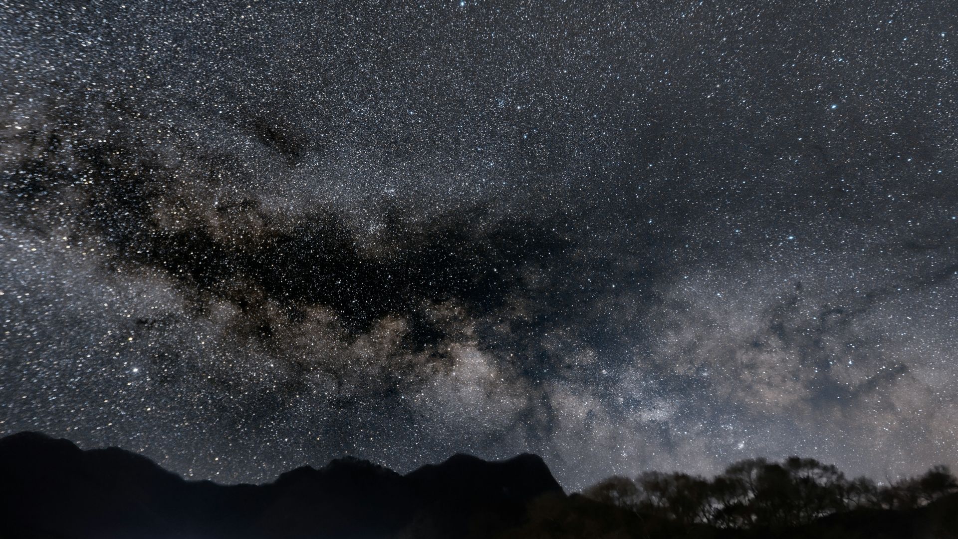 The milky way shines over a tranquil landscape.