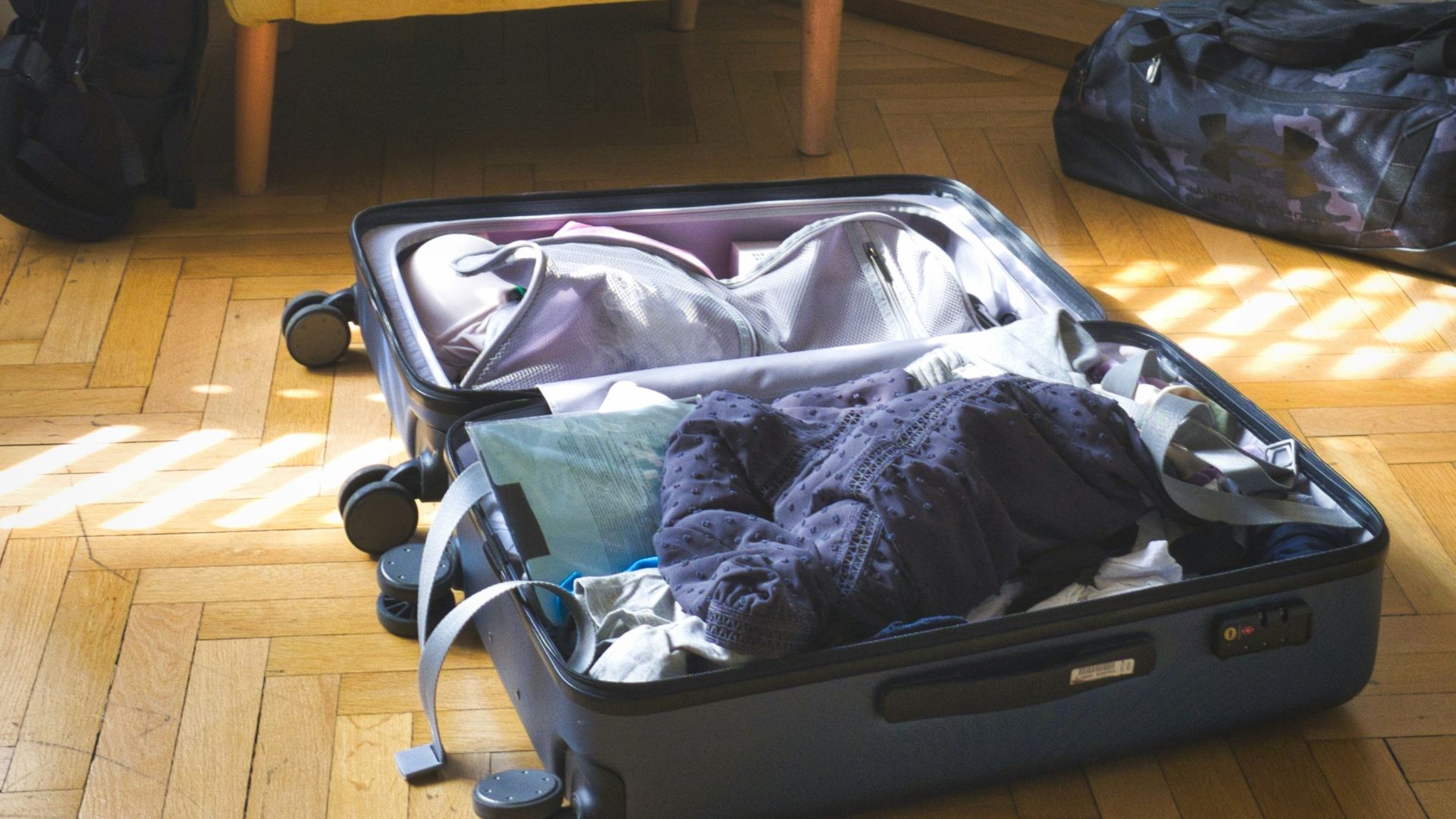 Open suitcase with clothes and armchair in a room