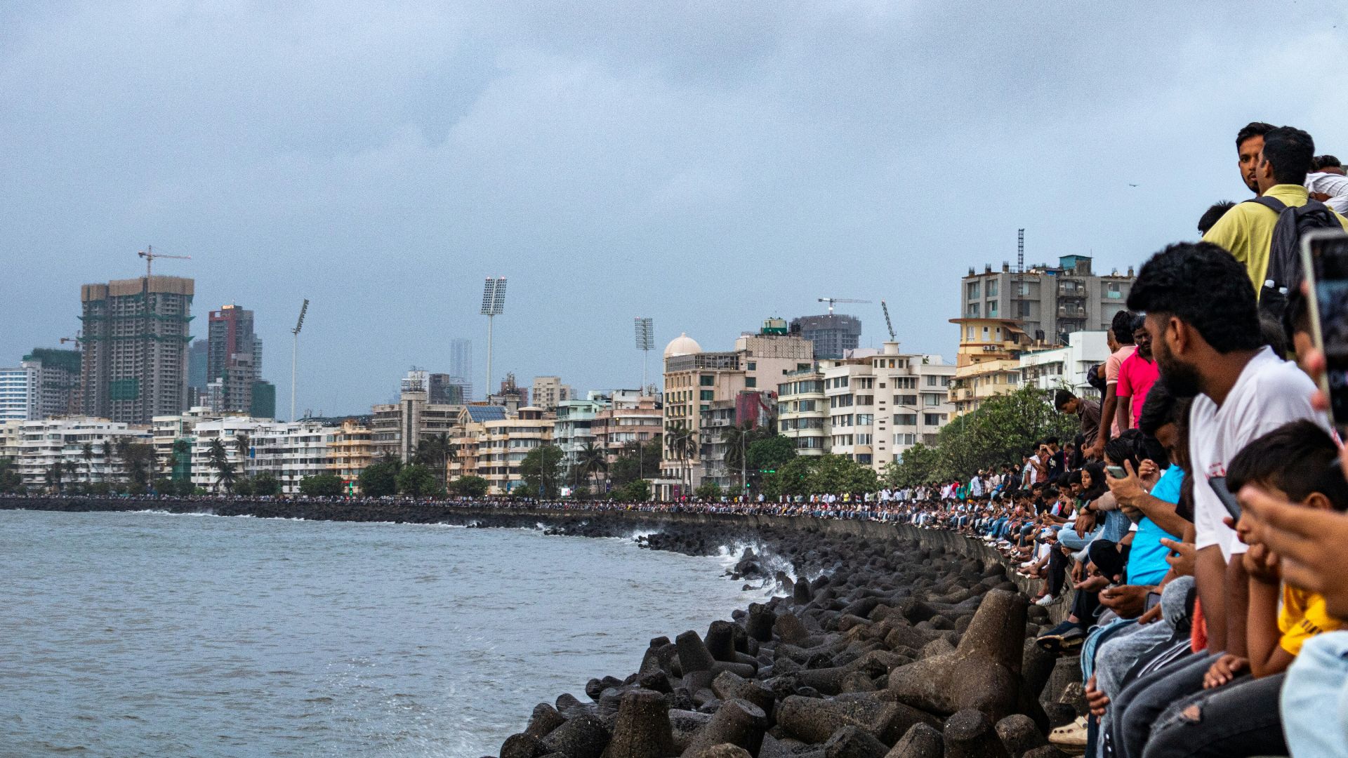 People watch the sea from a city's shore.