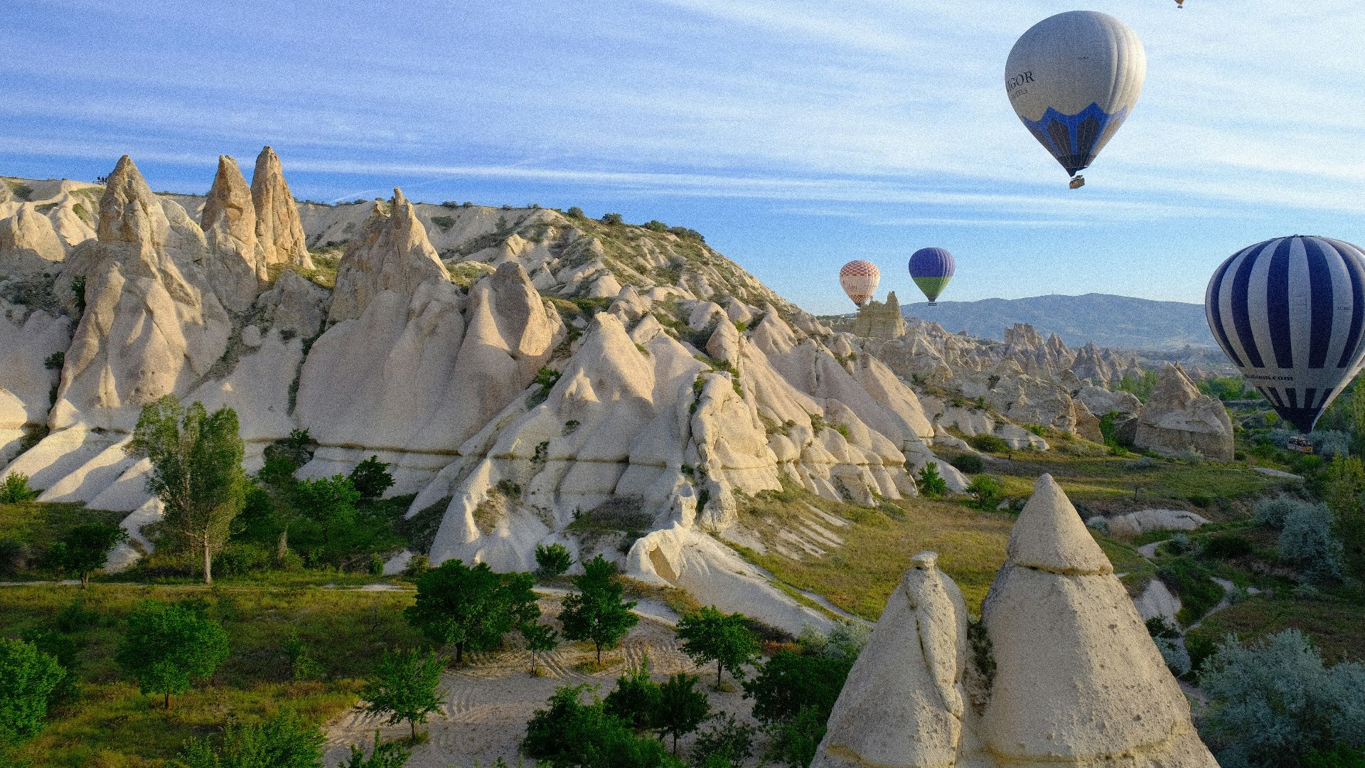 A group of hot air balloons flying over a valley
