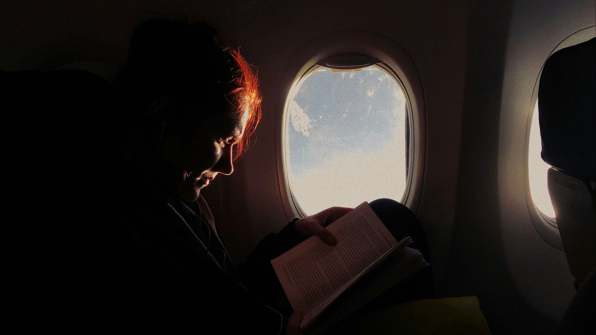 woman reading book in airplane