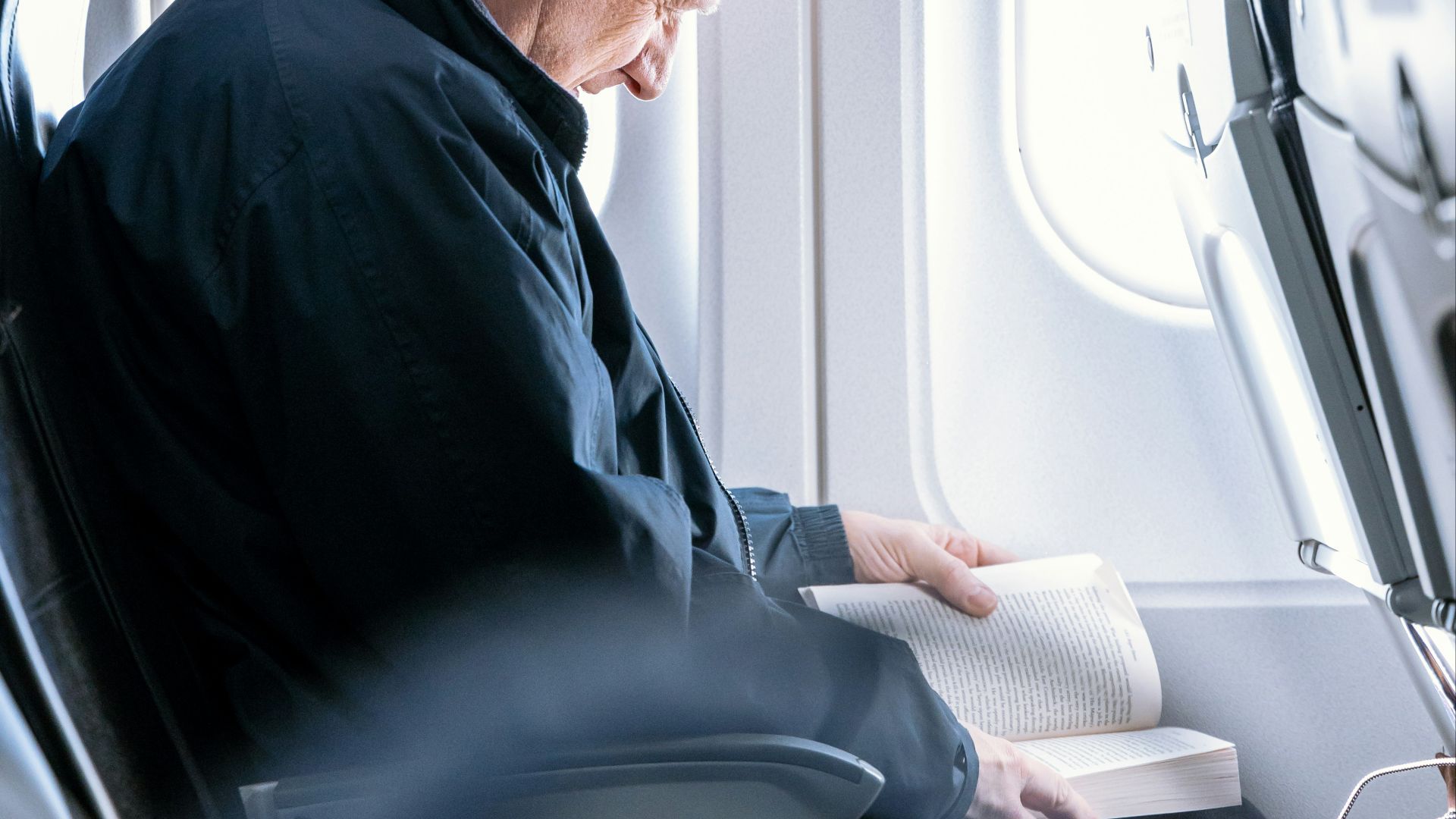 a man reading a book on an airplane