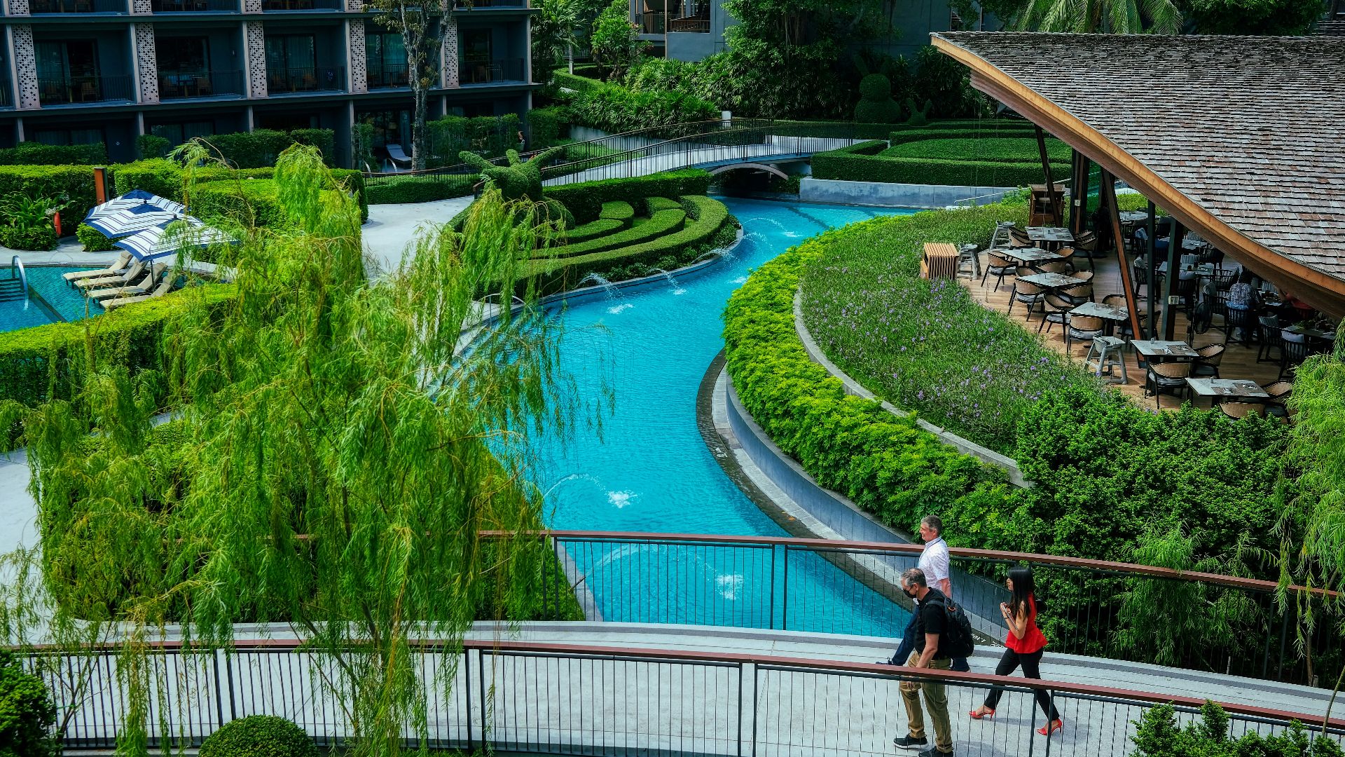 a couple of people walking across a bridge over a river
