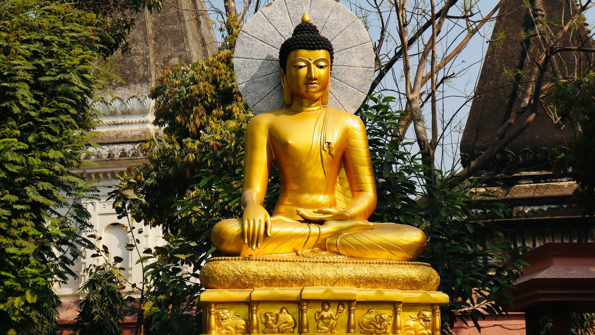 a golden buddha statue sitting in front of a building