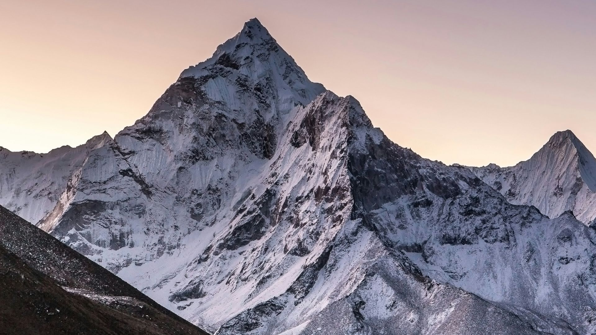 a mountain range covered in snow at sunset