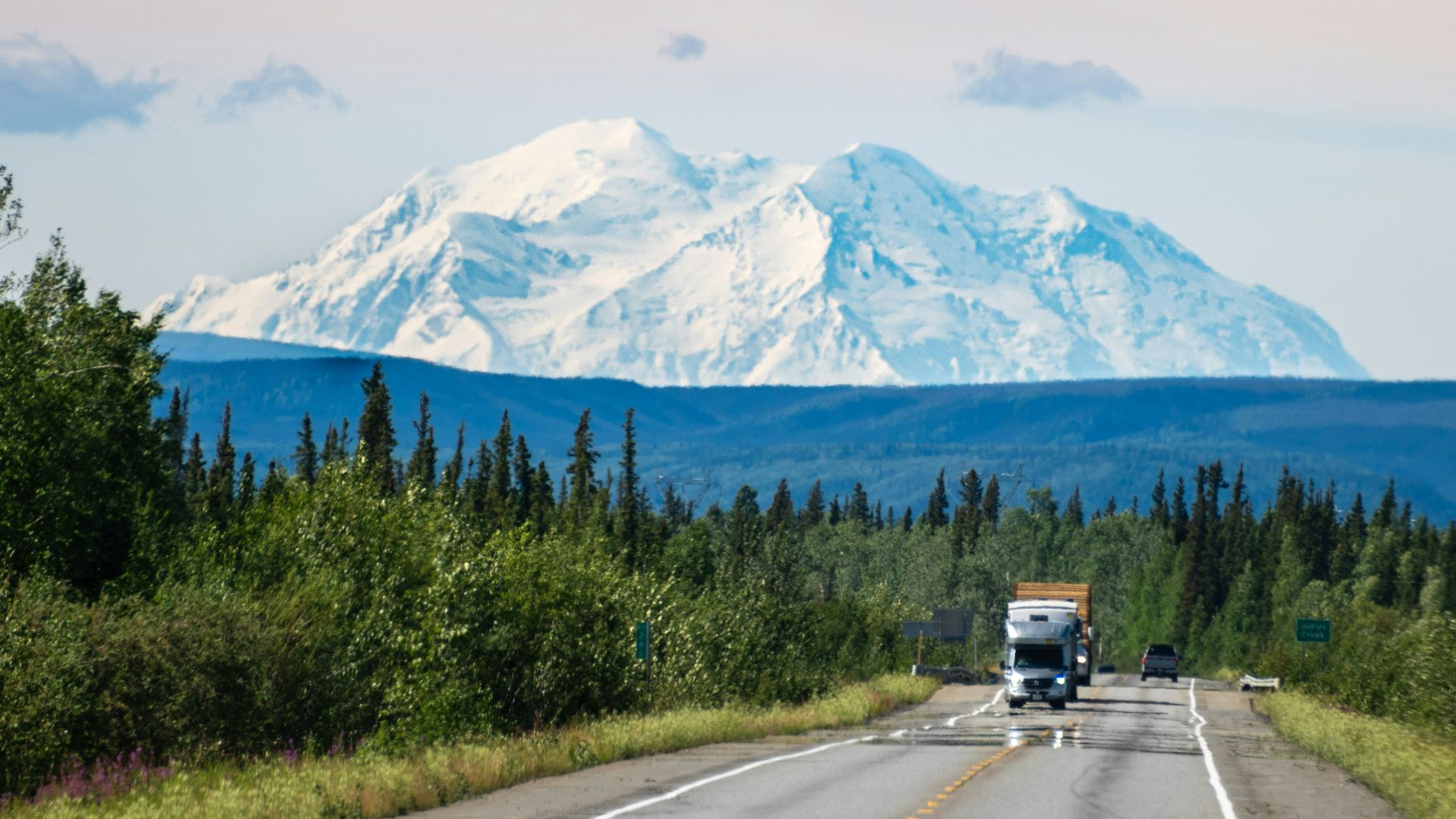 A truck driving down a road with a mountain in the background