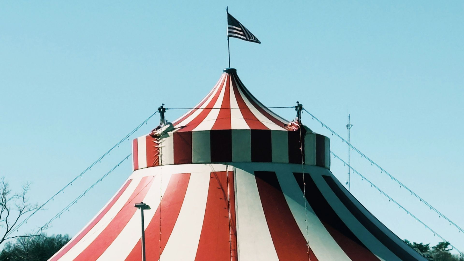 Circus tent with american flag under blue sky.
