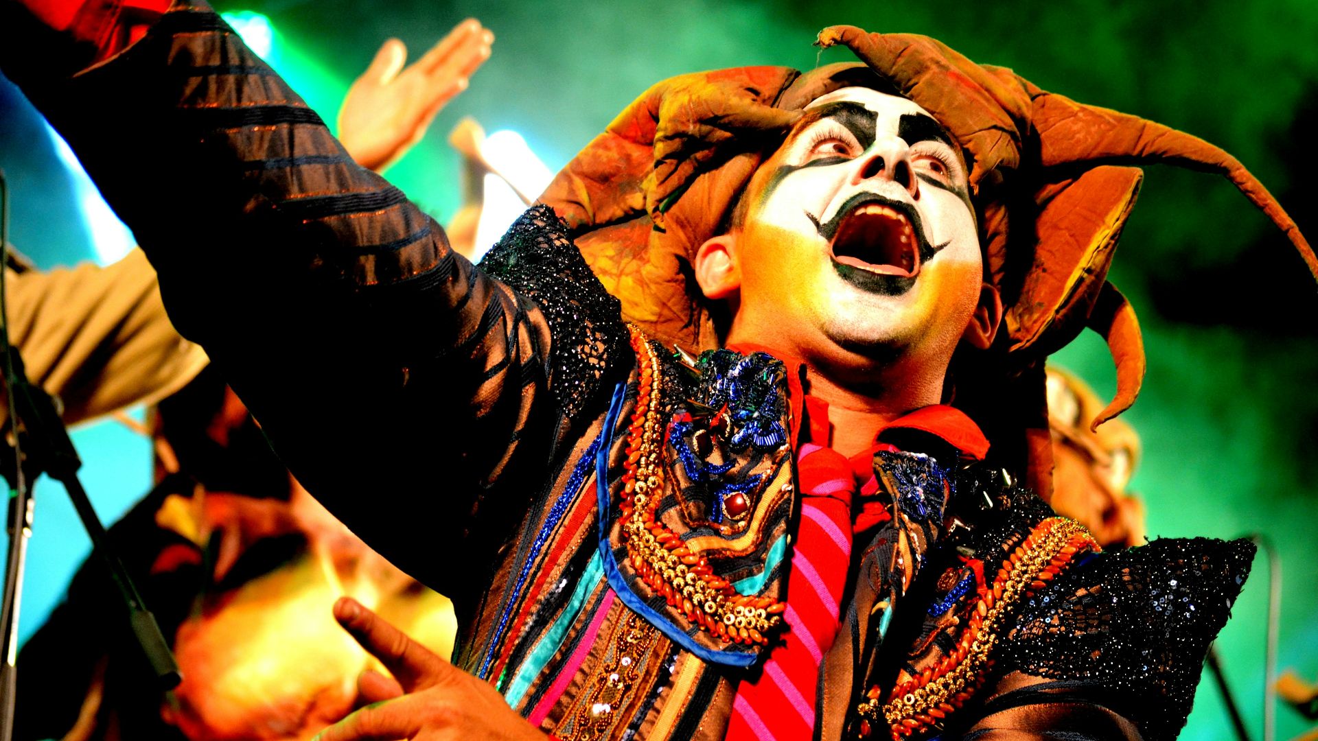 a man dressed as a clown with his hands in the air