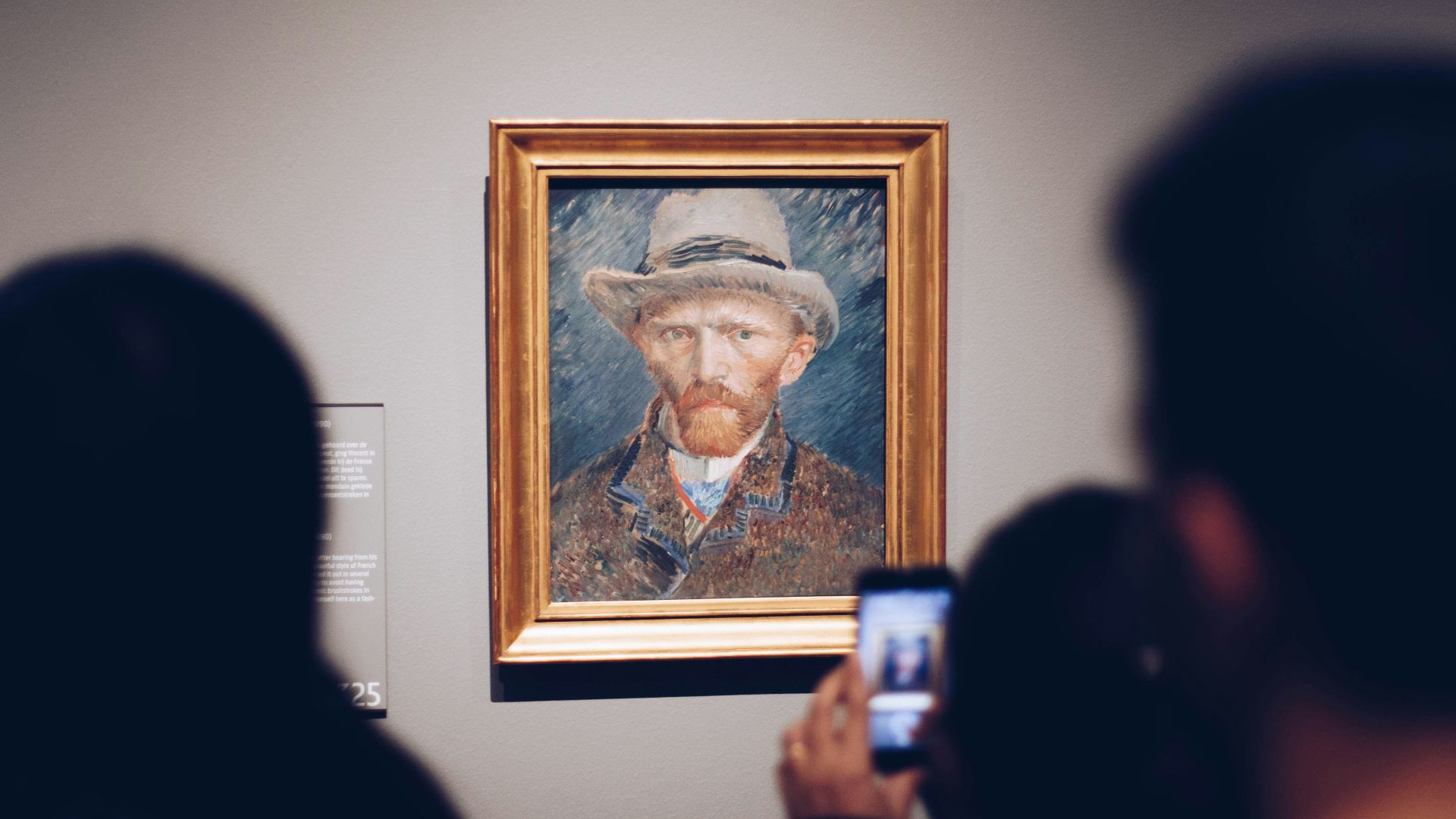 person taking picture of man wearing brown hat painting