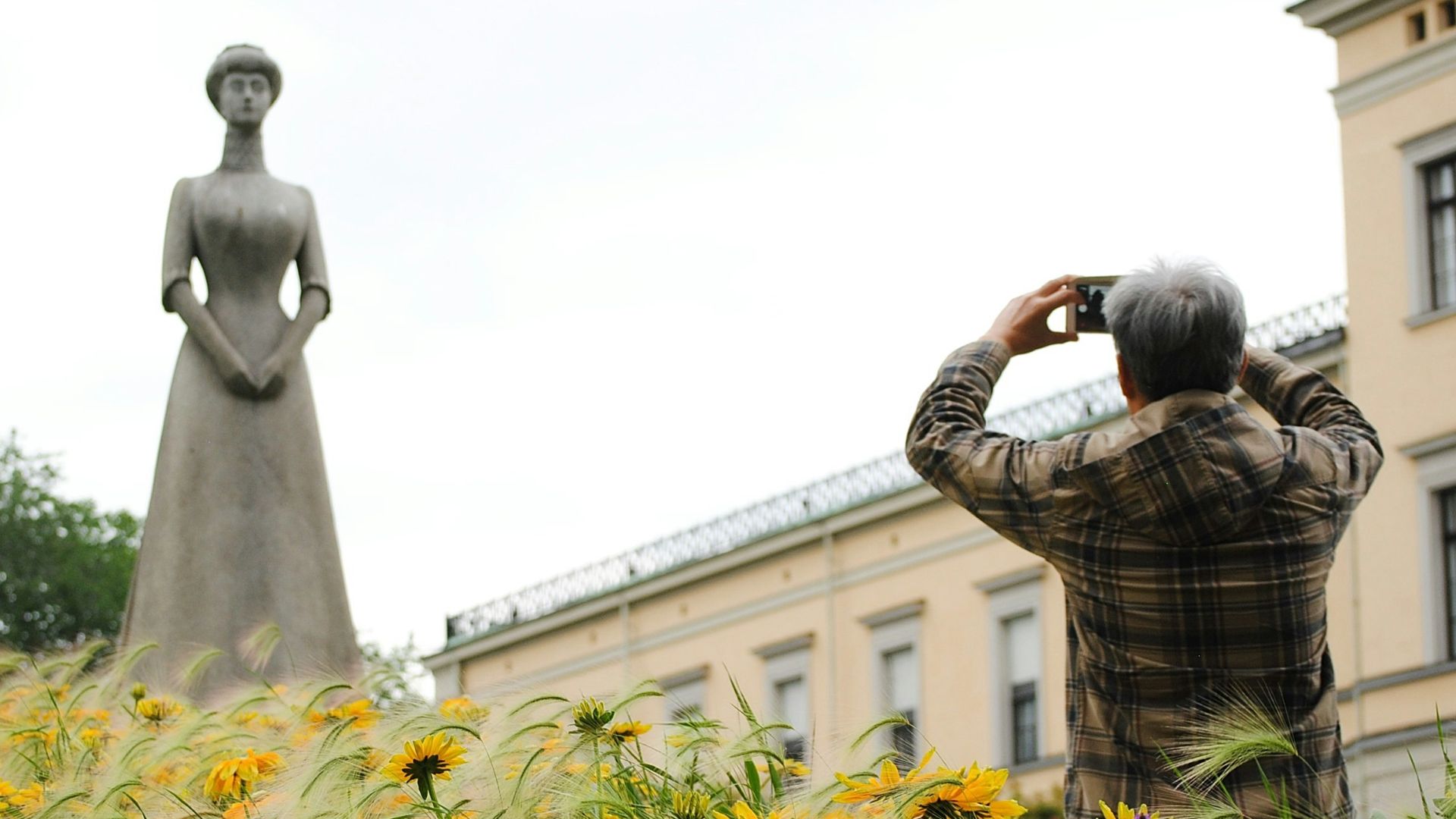 man standing while taking picture of woman statue