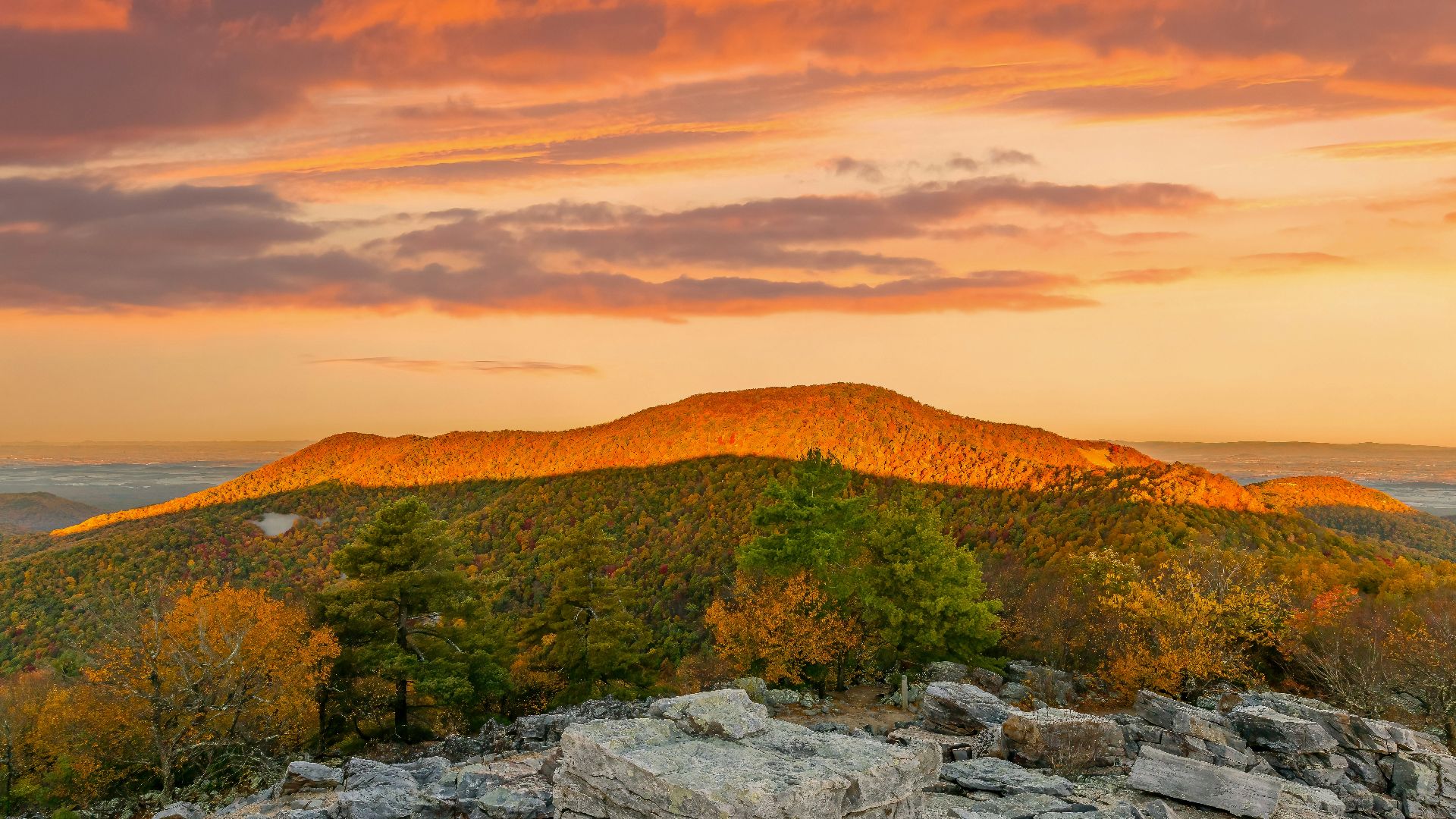 A view of a mountain with a sunset in the background