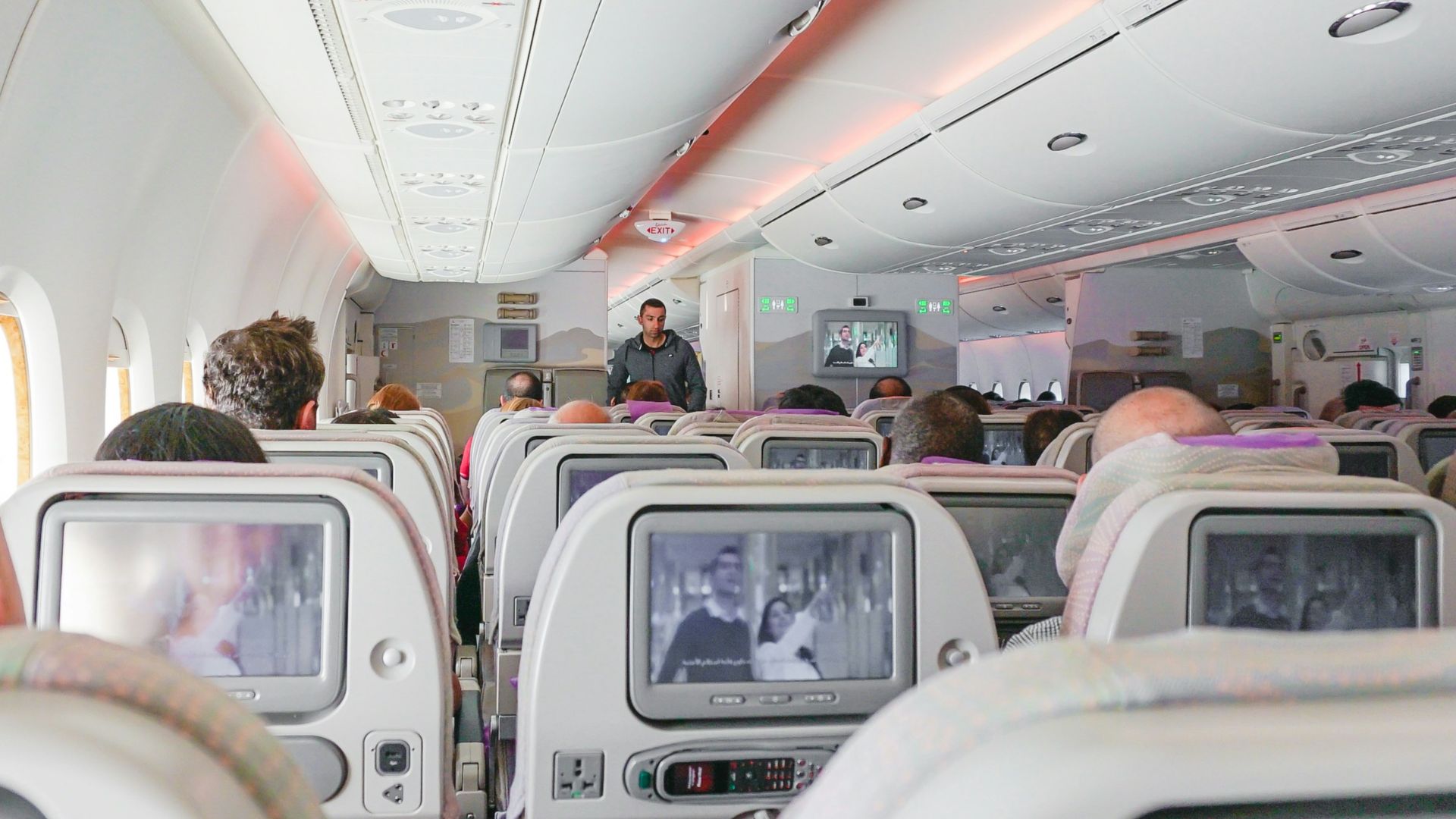 man walking down the aisle of airplane
