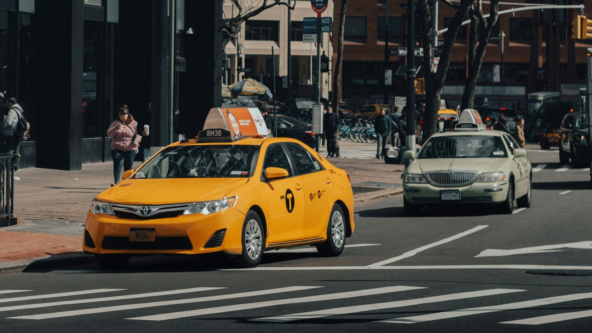 yellow taxi cab on road near building during daytime