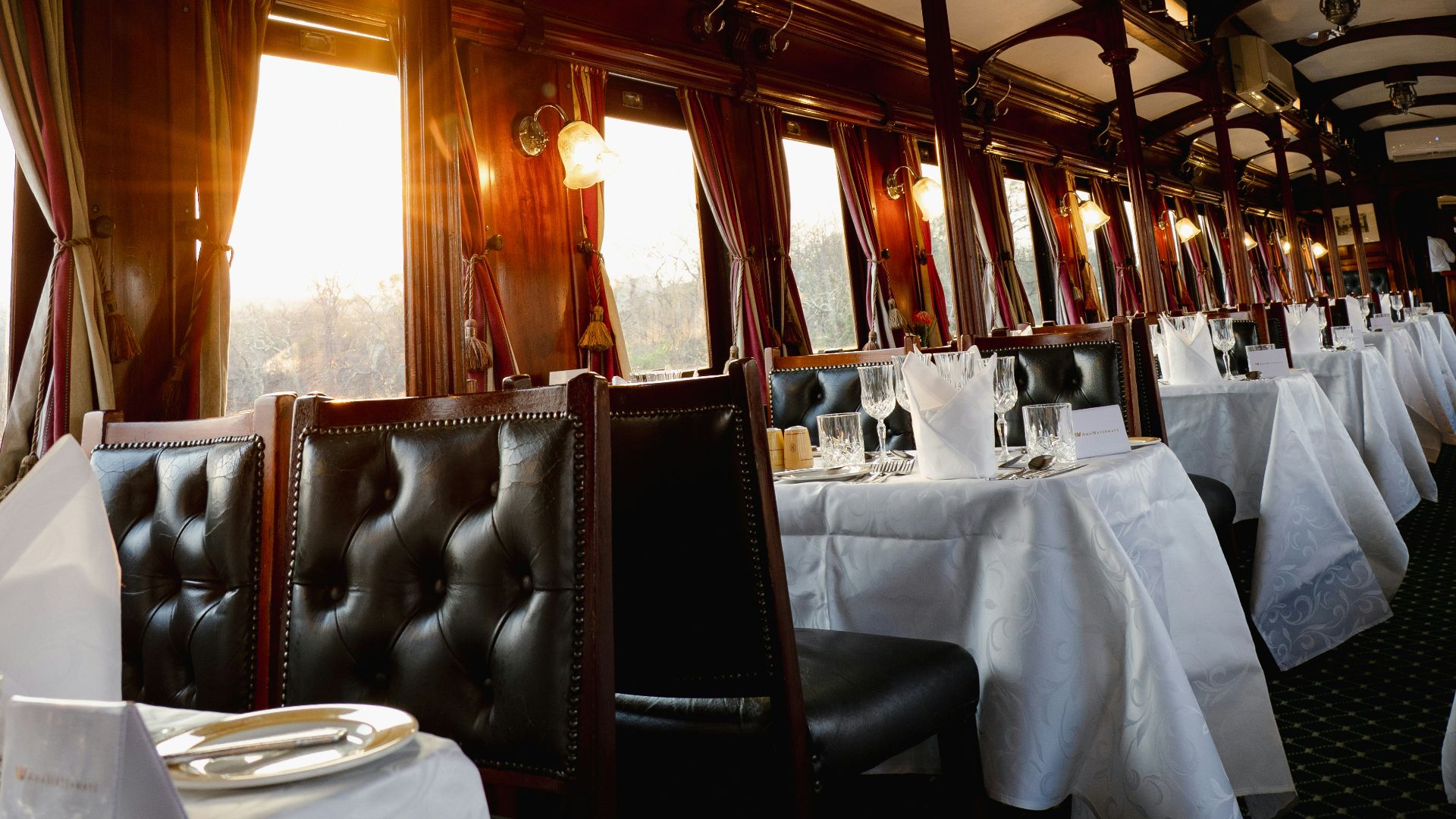 Elegant dining car interior with tables set for dinner.