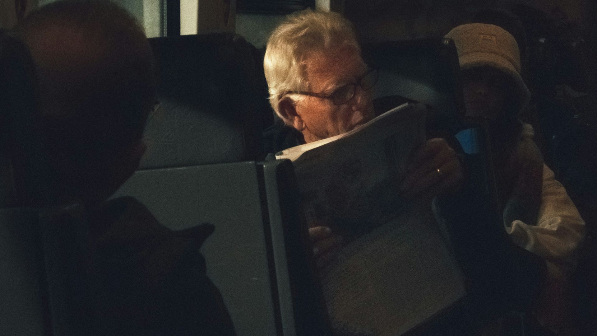 a group of people sitting in a bus looking at a laptop
