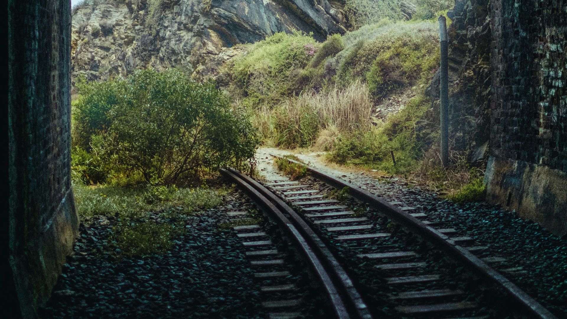 a train track going through a tunnel with a mountain in the background