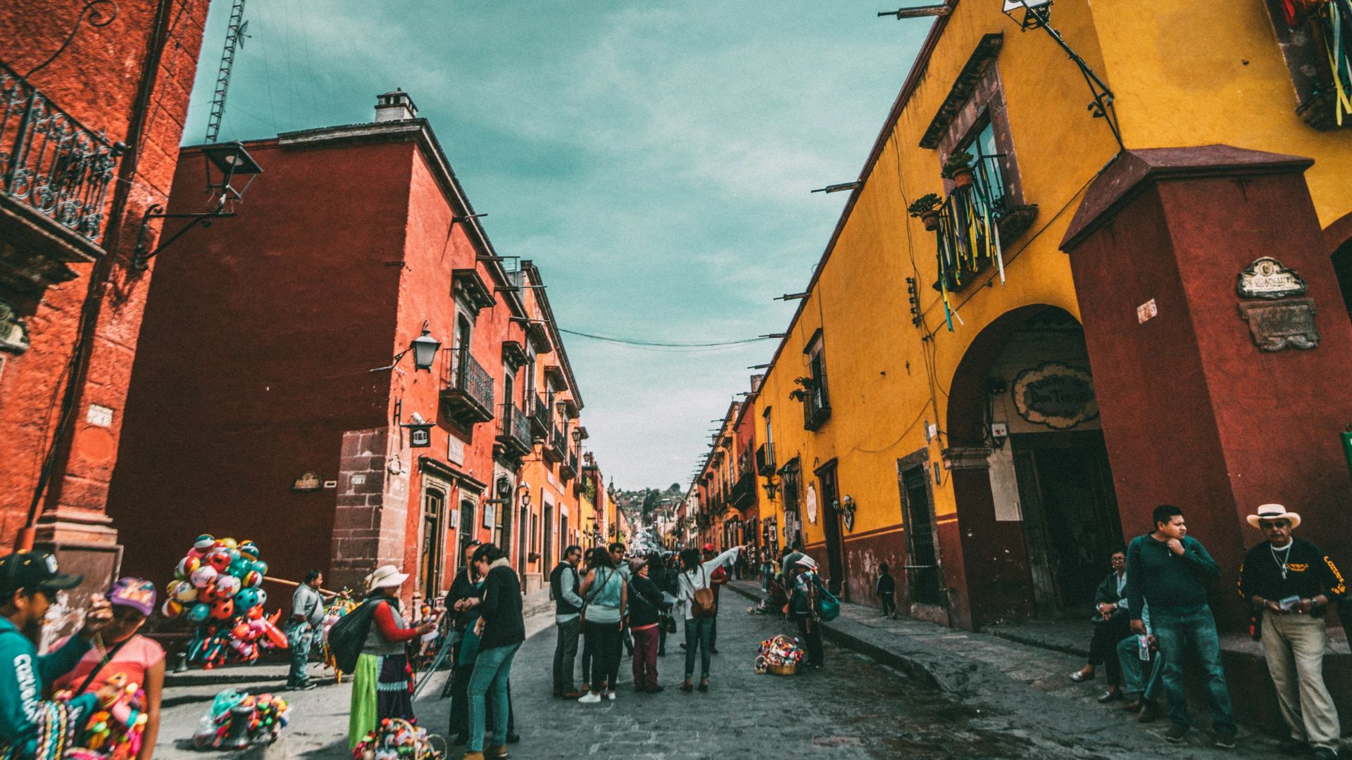 people standing on corner road near concrete buildings during daytime