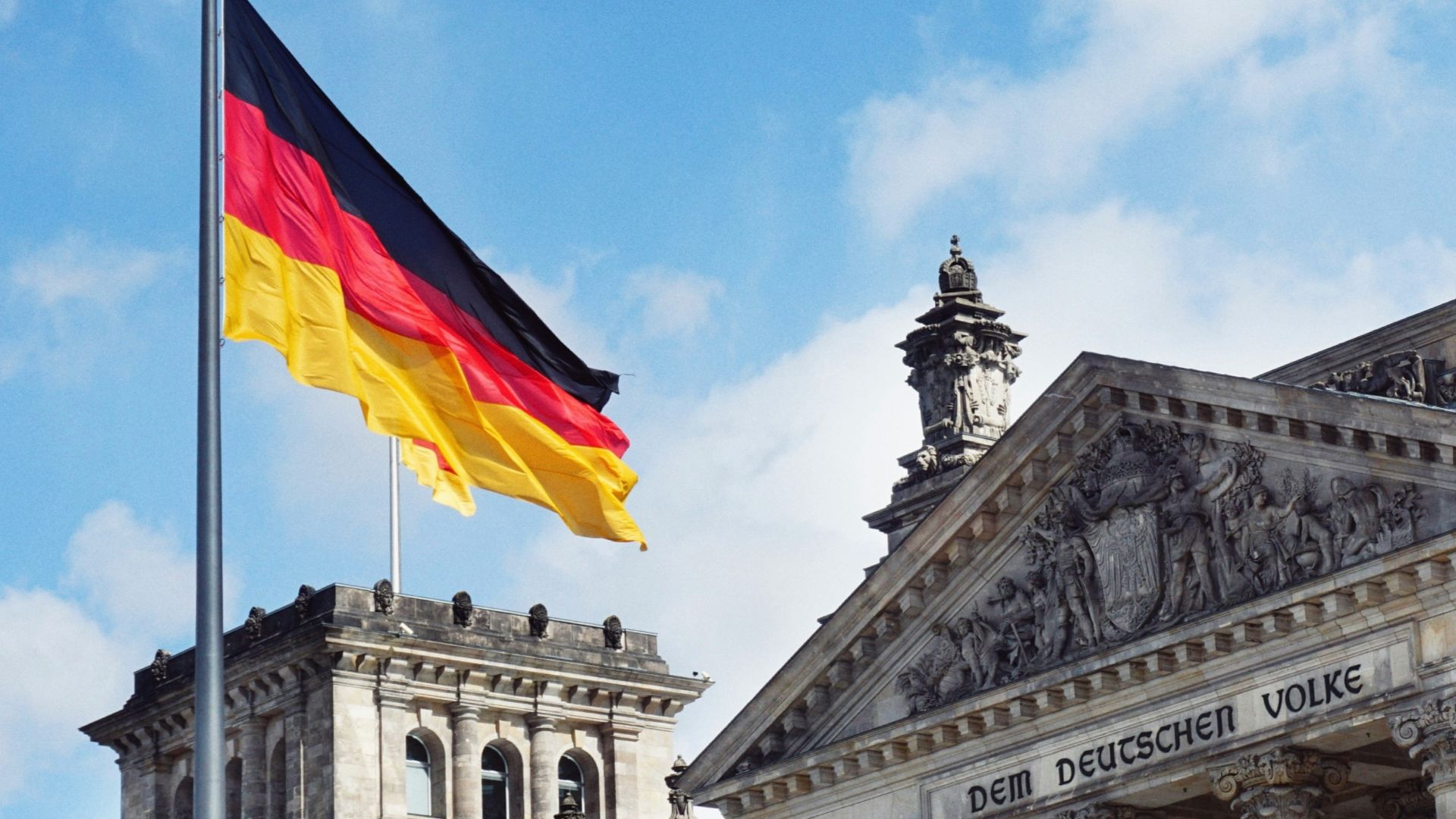 white concrete building with flags on top under blue sky during daytime