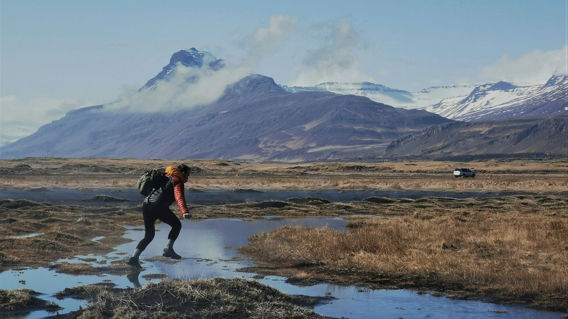 A hiker steps across a puddle in the wilderness.