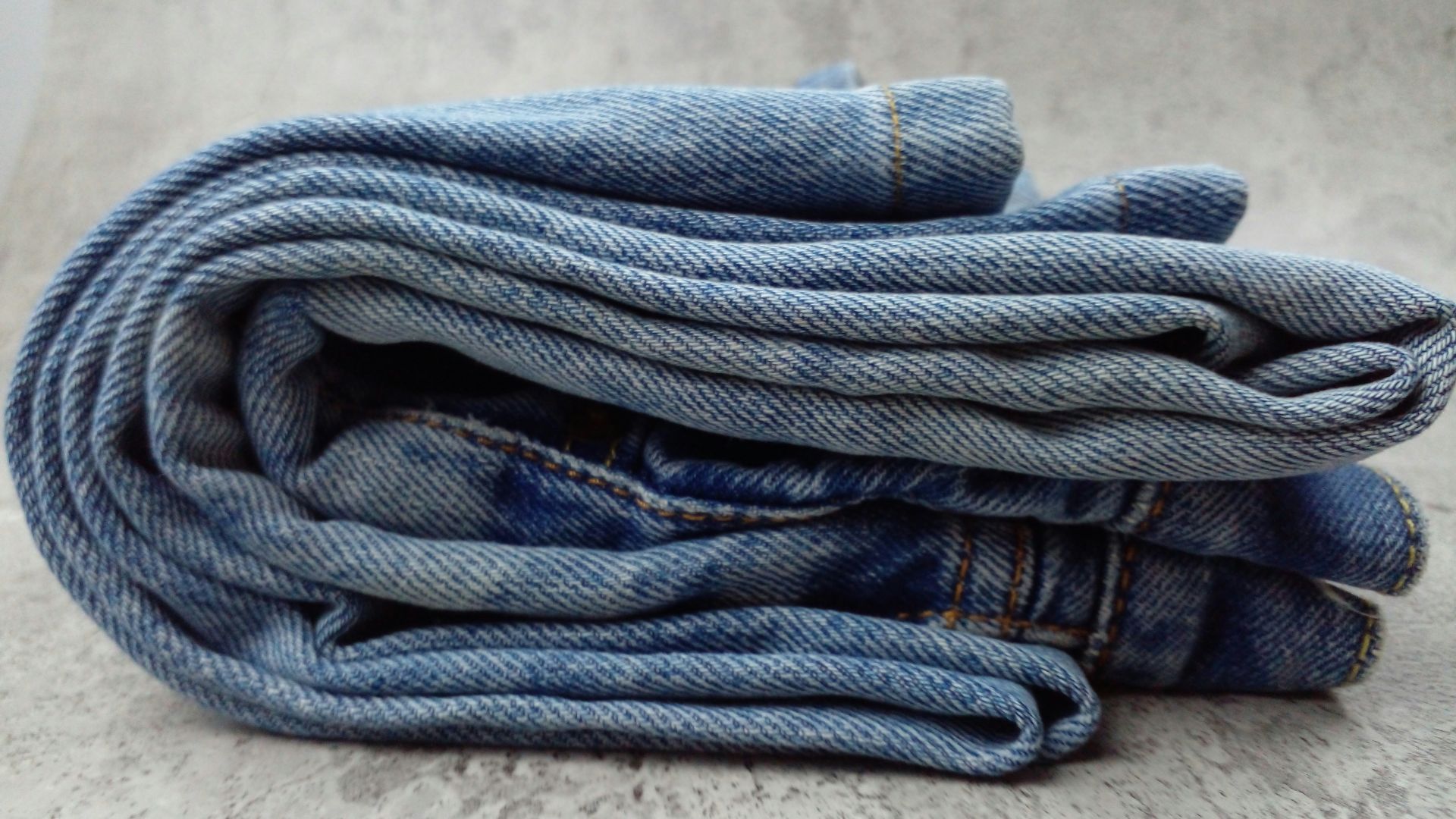 A pile of blue jeans sitting on top of a white floor