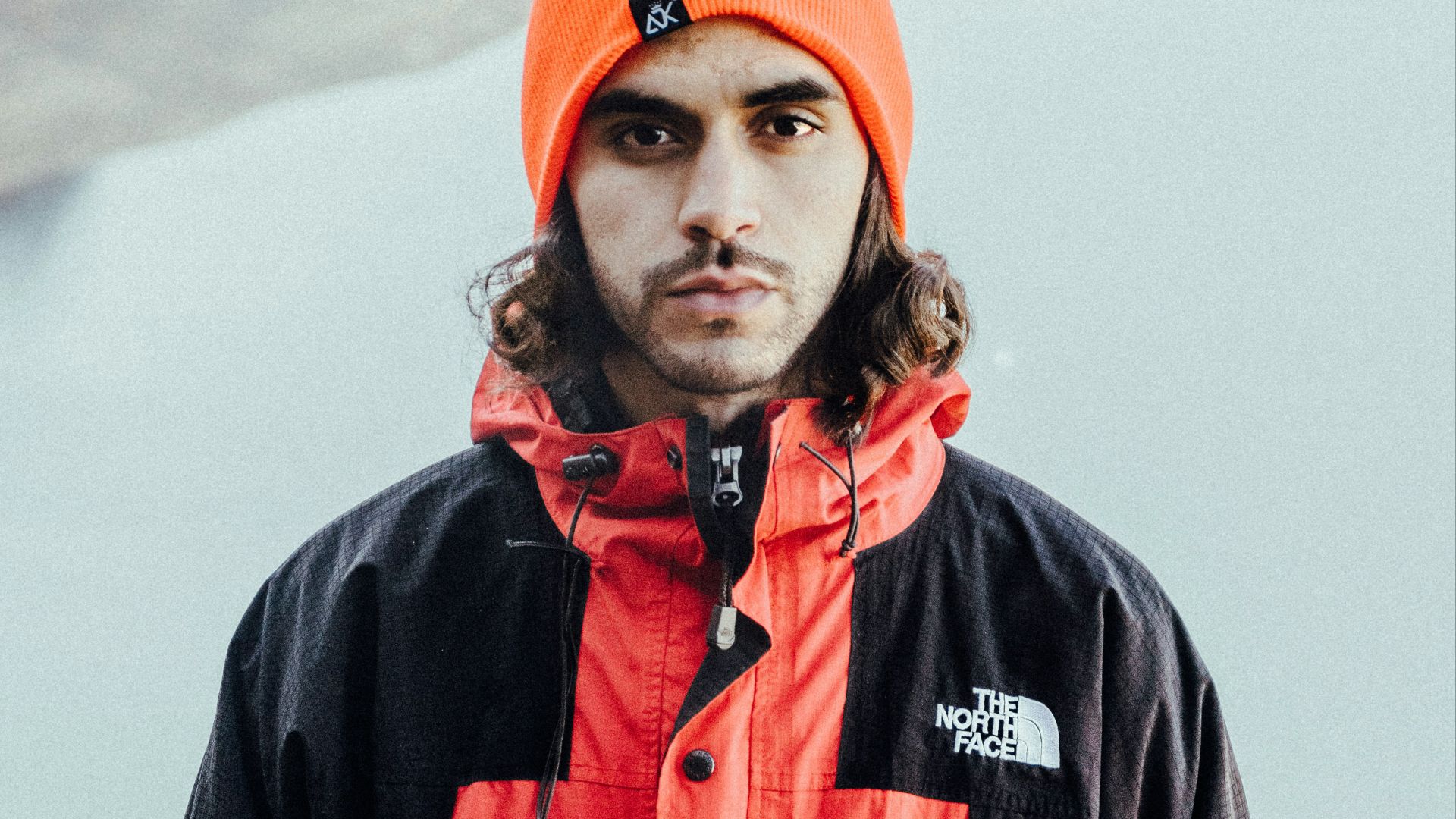 man in black and red zip up jacket and orange knit cap