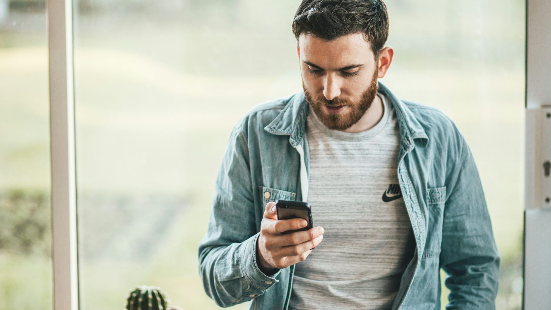 man holding a smartphone near the window