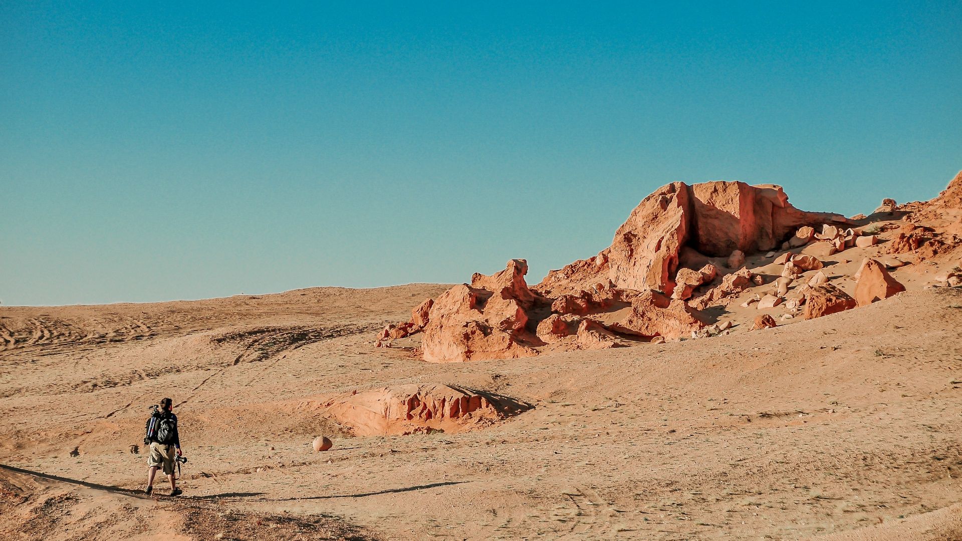 man in black jacket walking on brown sand during daytime