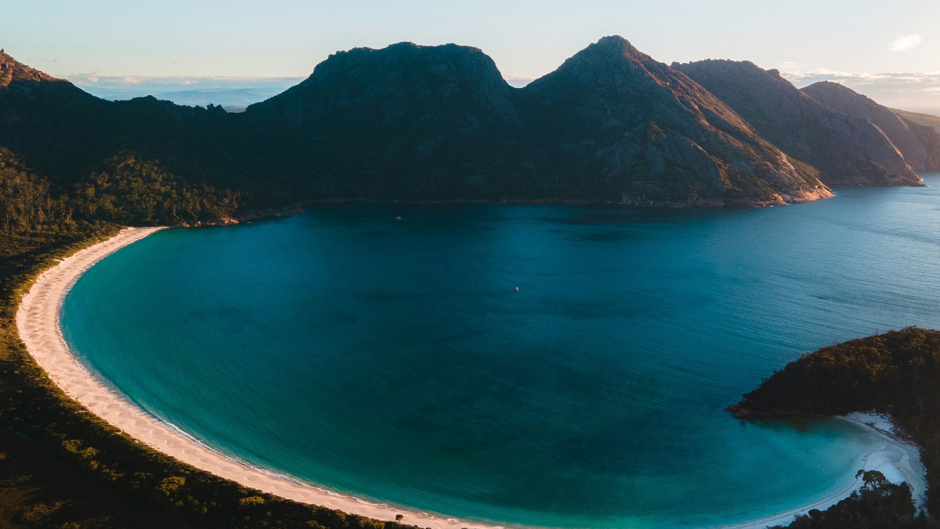 blue body of water near mountain during daytime