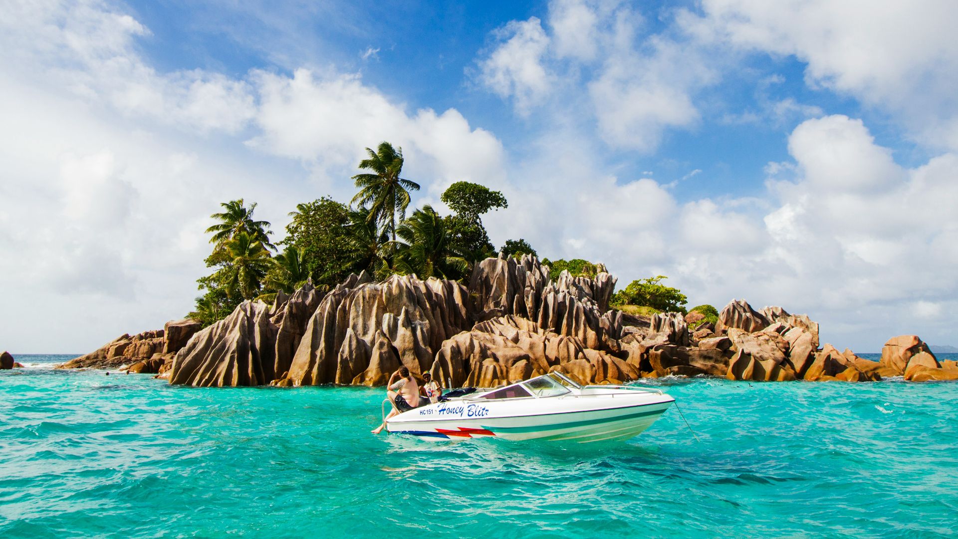 white and blue boat on sea near green palm trees during daytime