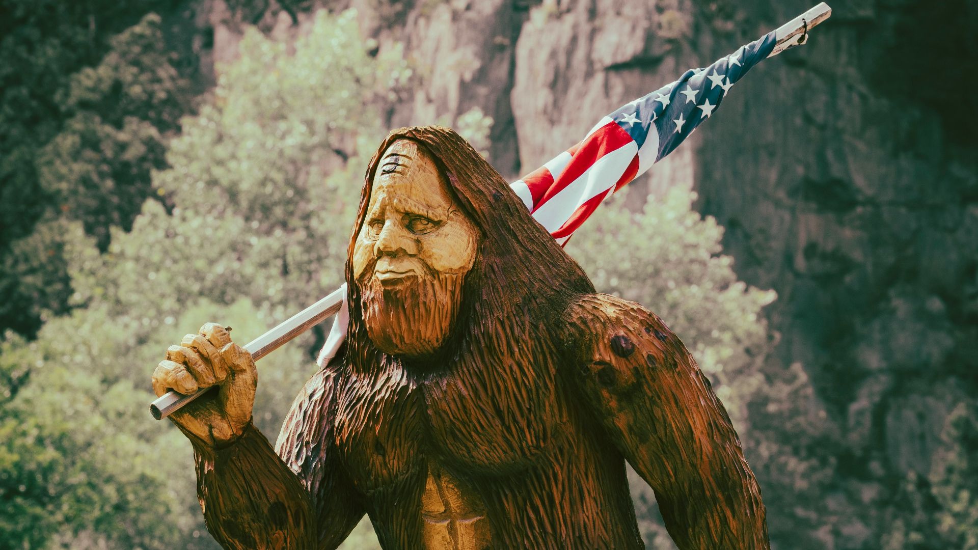 a statue of a bigfoot holding an american flag