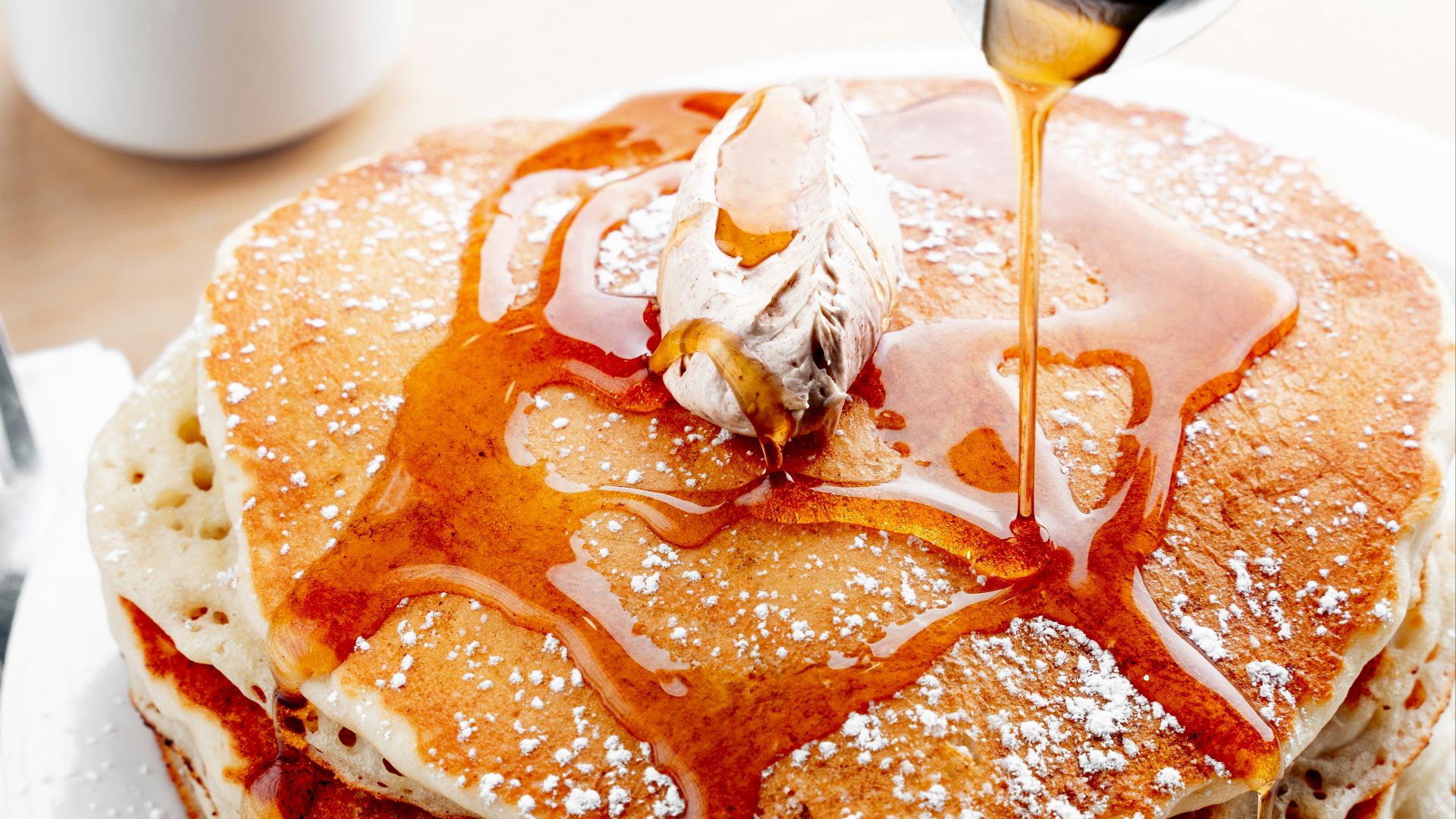 a stack of pancakes with syrup being drizzled on top