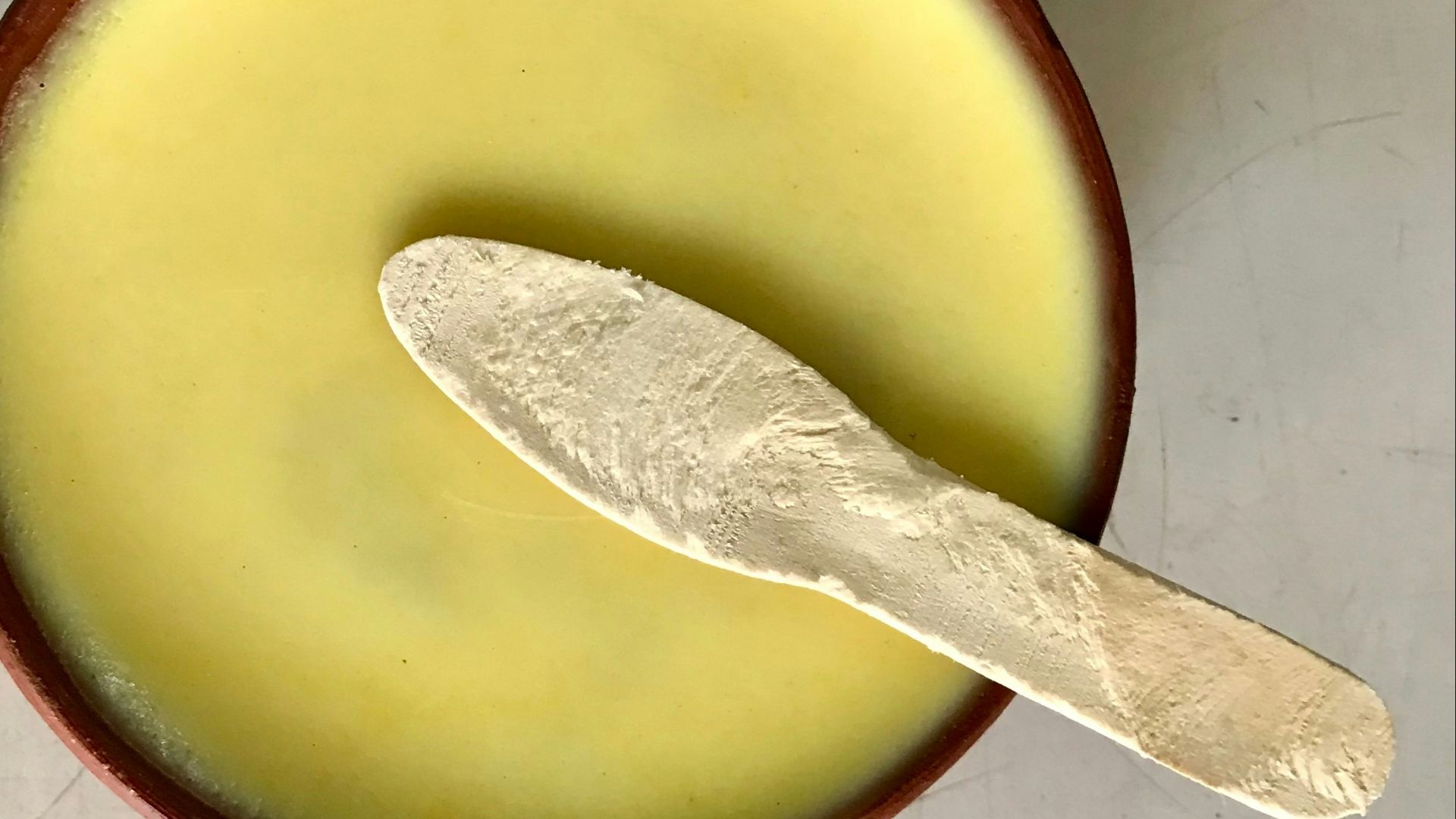 A spoon in a bowl with a liquid inside of it