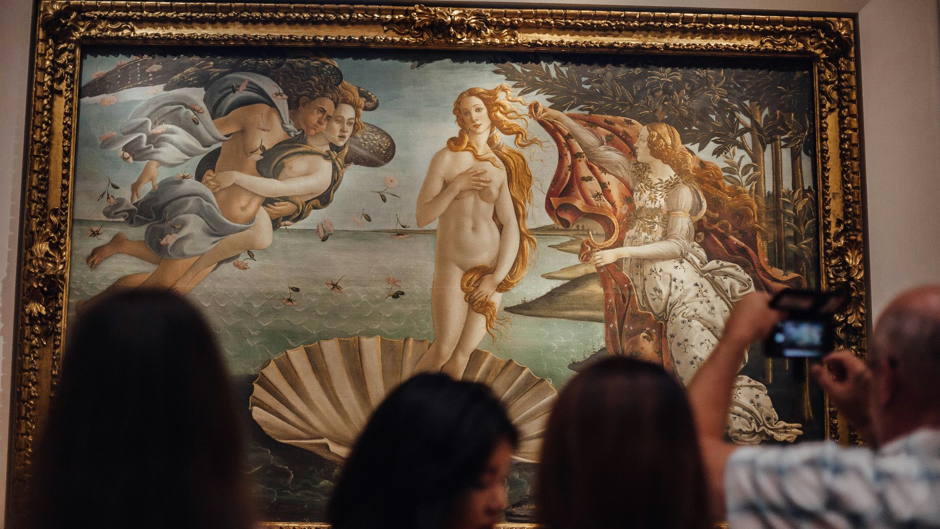 people in front of gold framed painting