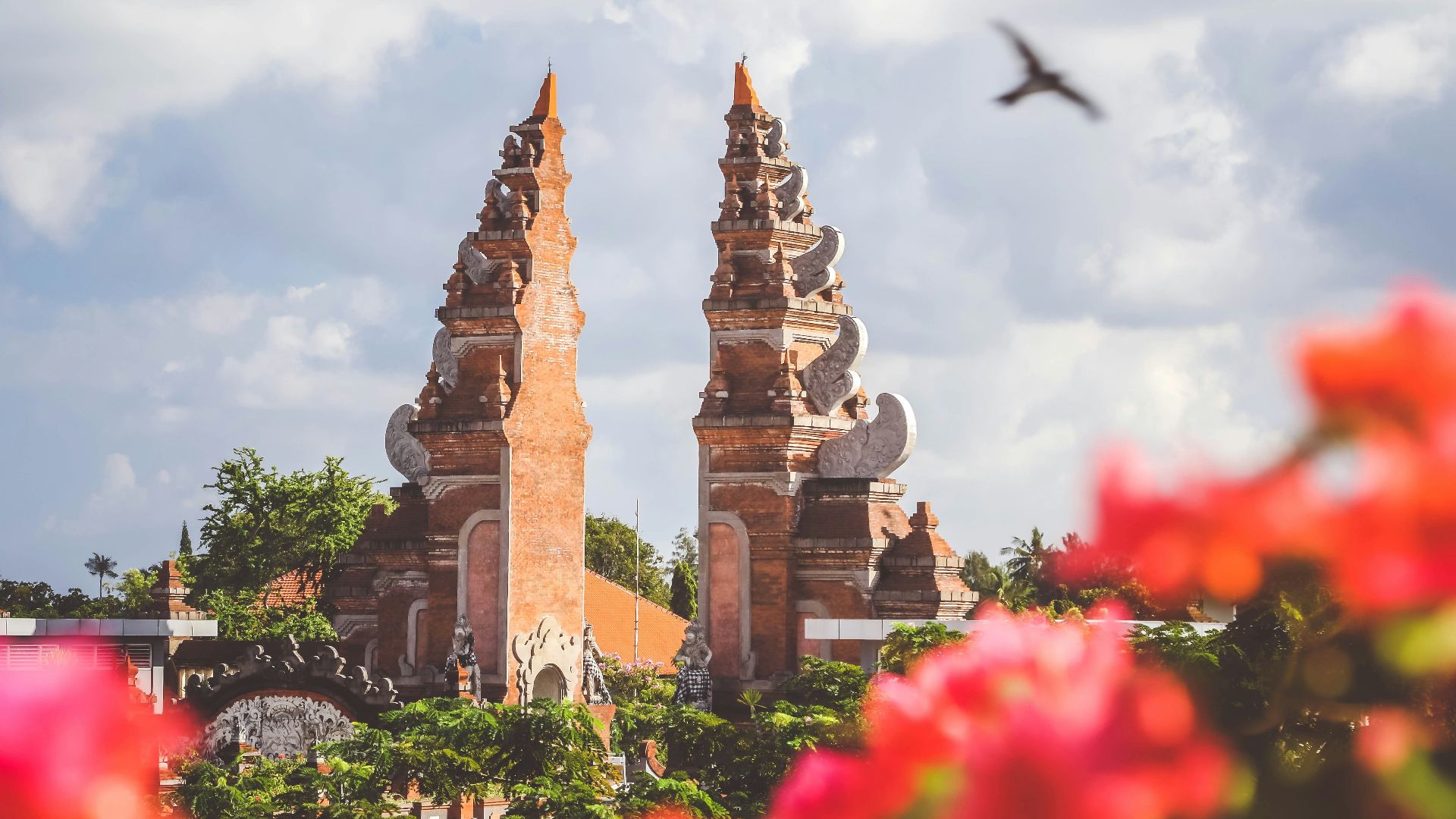 bird flying over brown concrete gate during daytime