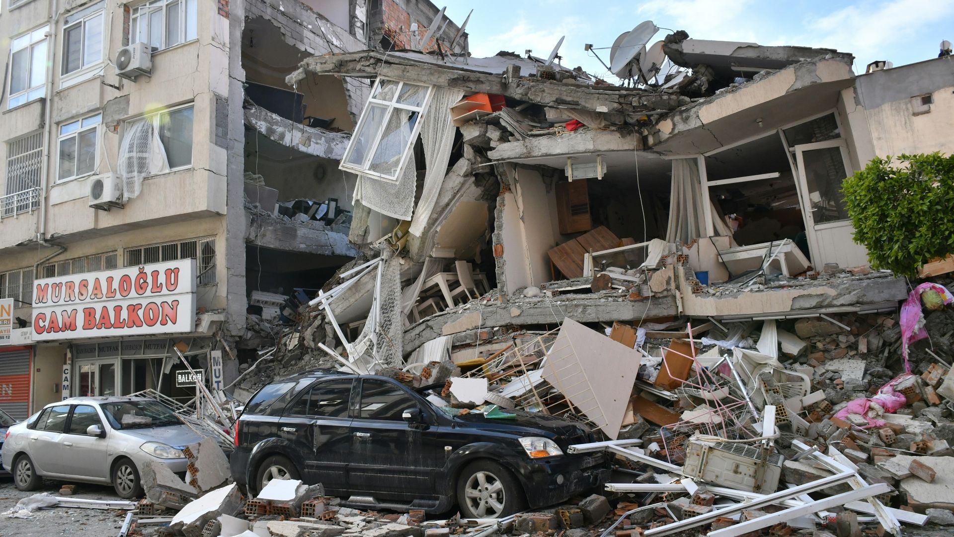 a car is parked in front of a destroyed building