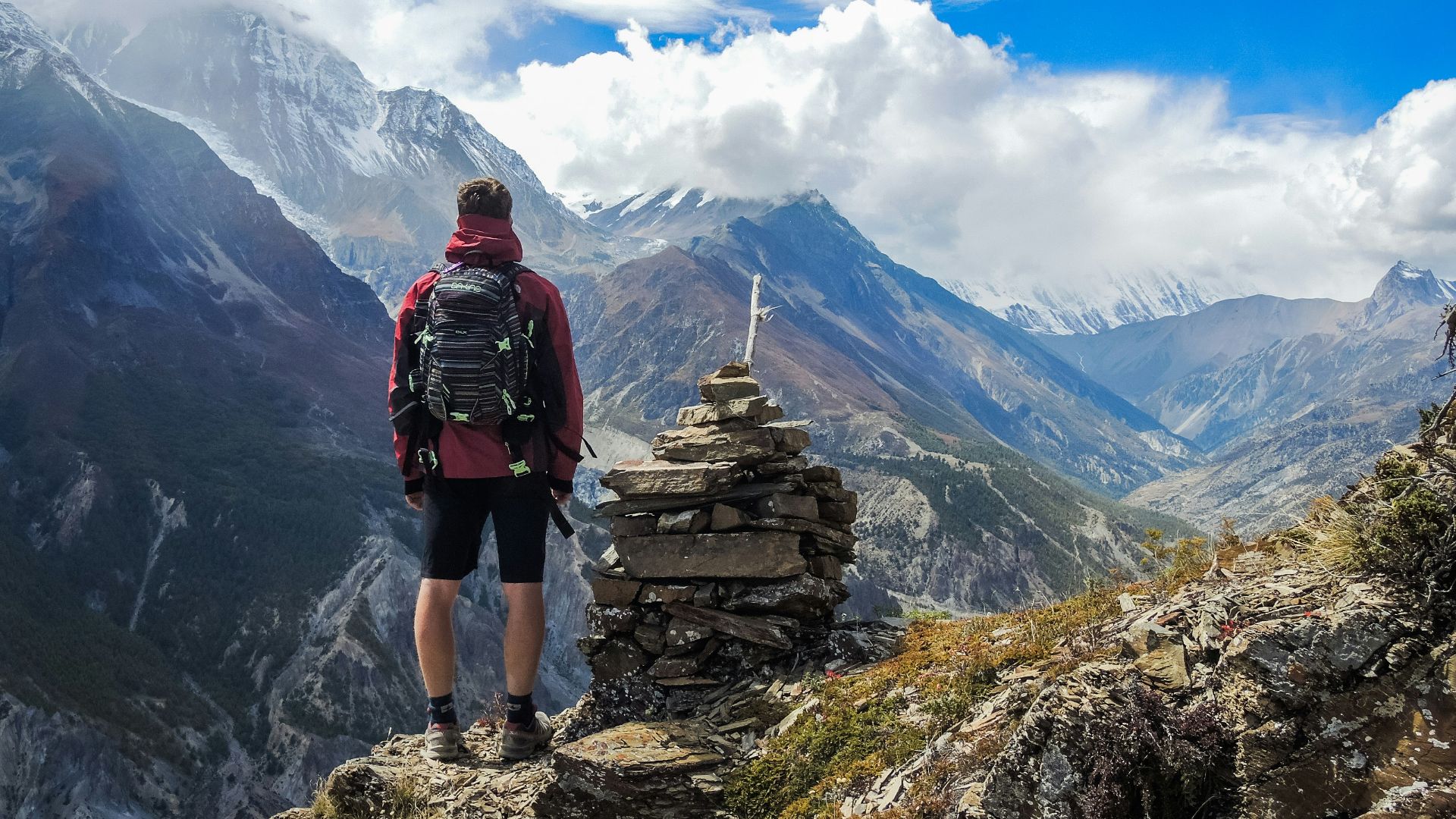 man standing on top of mountain beside cairn stones