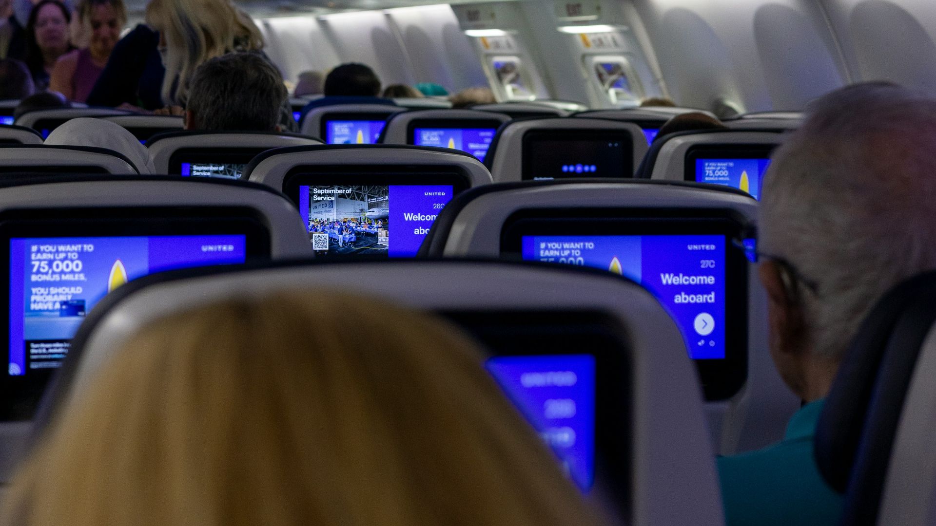 Interior view of airplane cabin with passengers and screens