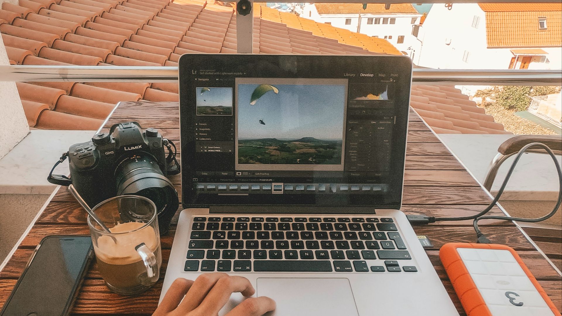 person holding MacBook Pro besides orange power bank